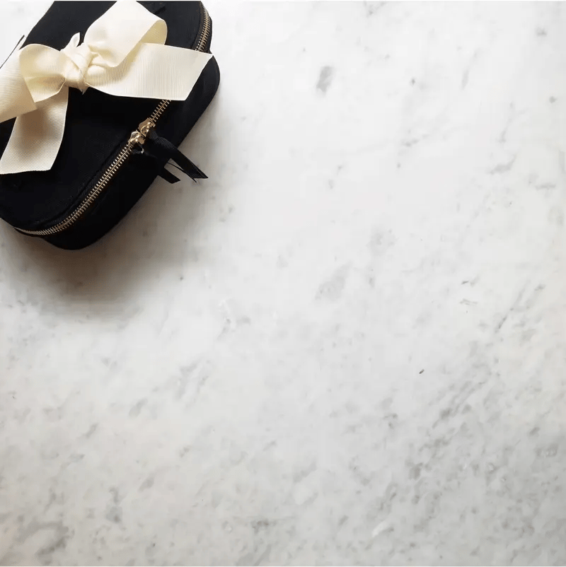 Bag-all black Weekender Gift Set 3-pack laundry and beauty case with cream bow on marble background