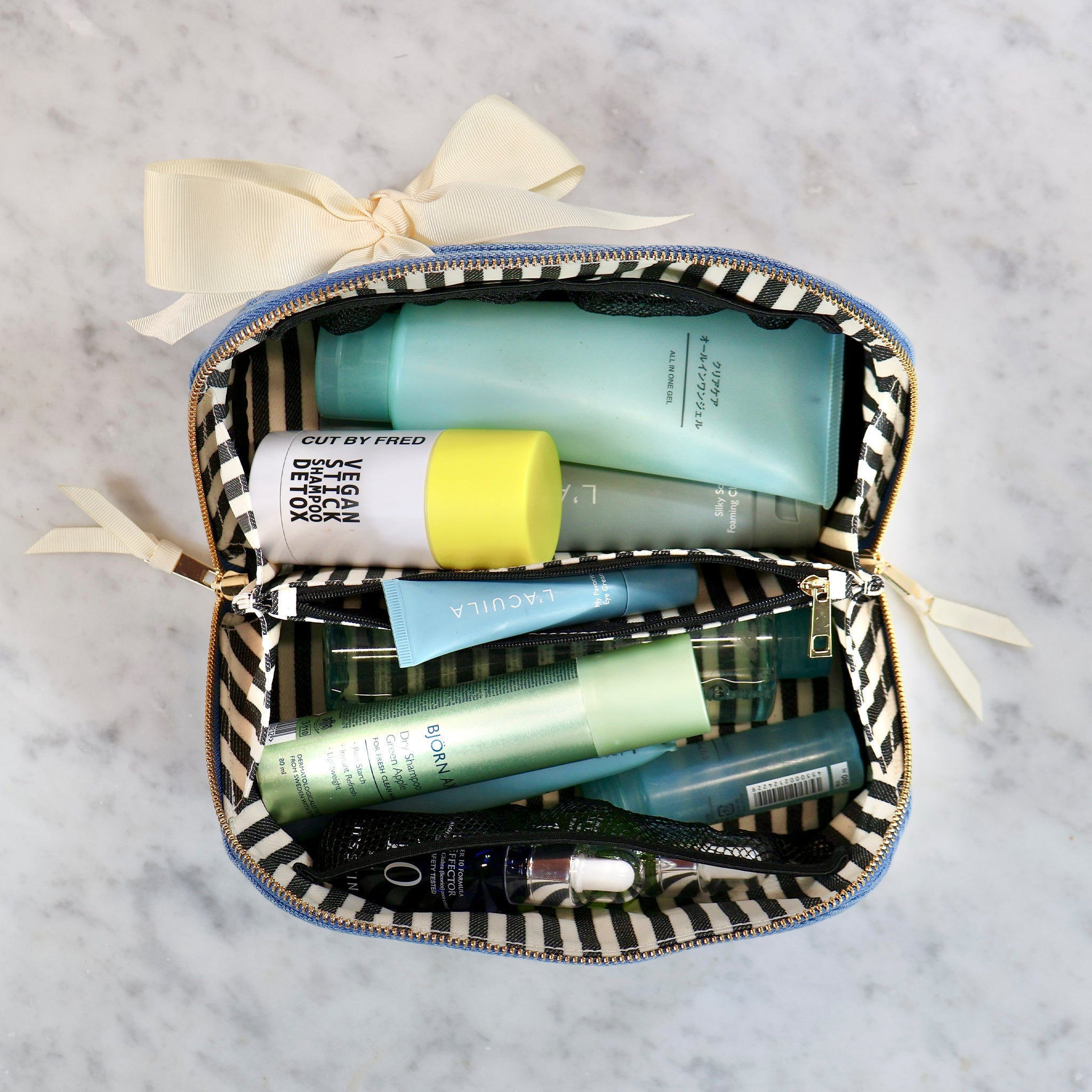 Bag-all expandable denim makeup bag with striped interior, neatly holding skincare and beauty products for easy organization