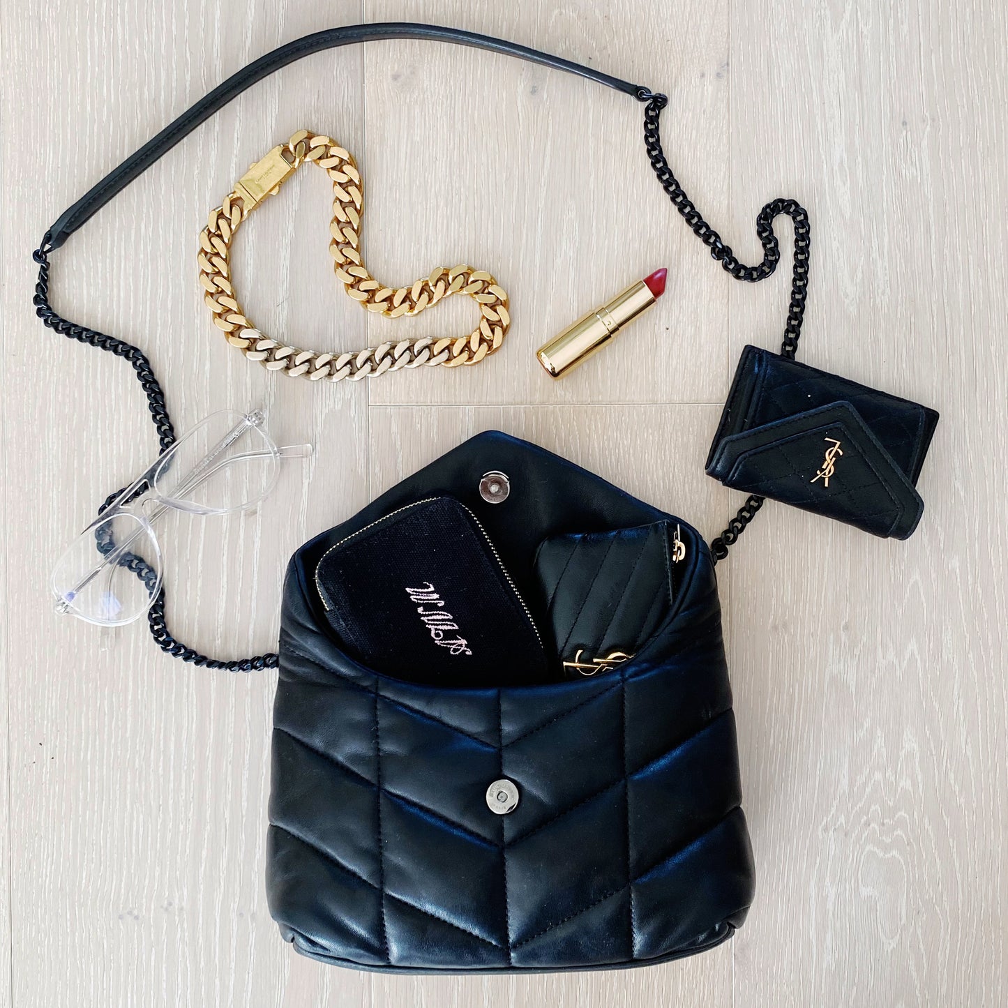 Bag-all black Jewelry/Trinket Box with gold zipper shown with luxury accessories including gold chain bracelet and lipstick, perfect for organizing small valuables while traveling or daily use