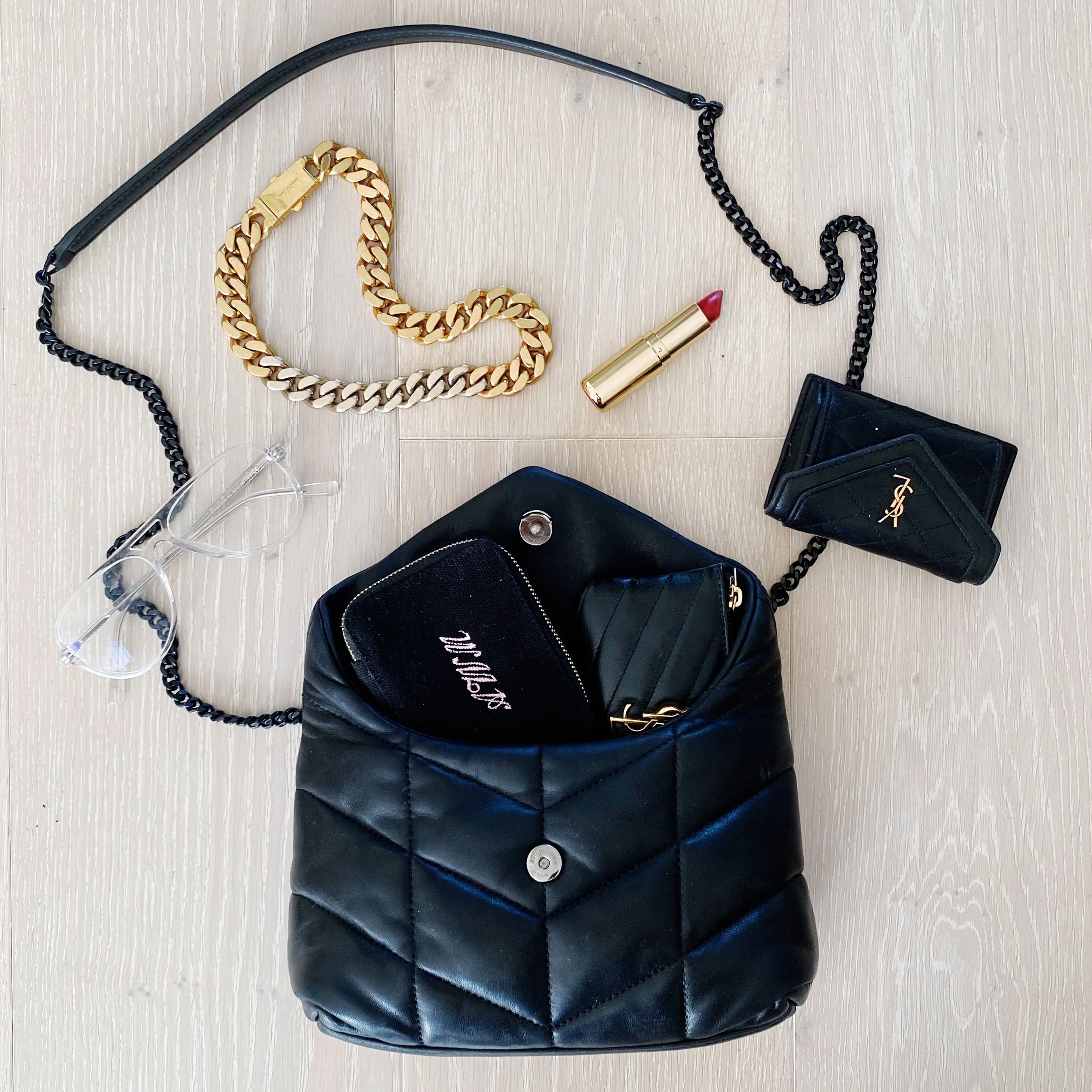 Bag-all black Jewelry/Trinket Box with gold zipper shown with luxury accessories including gold chain bracelet and lipstick, perfect for organizing small valuables while traveling or daily use