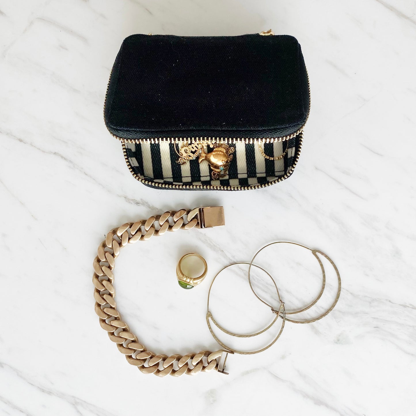 Bag-all Black Jewelry Box with striped lining and gold zipper, displayed with gold bracelet, ring and silver hoop earrings on marble surface