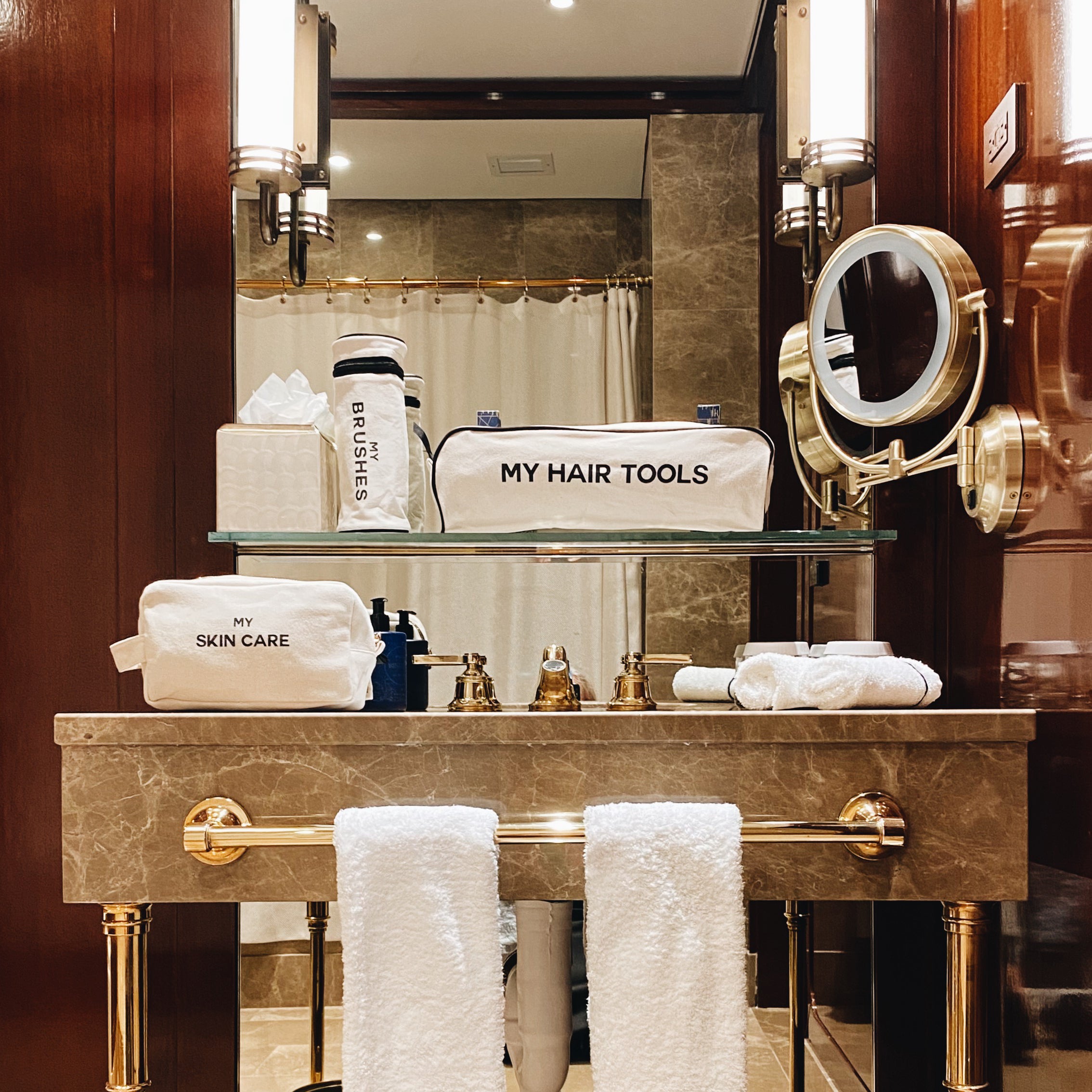 Bag-all Pamper Gift Set Deal 3-Pack Cream featuring cotton organizer pouches for hair tools and skincare, displayed on luxury marble bathroom vanity with gold accents and mirror