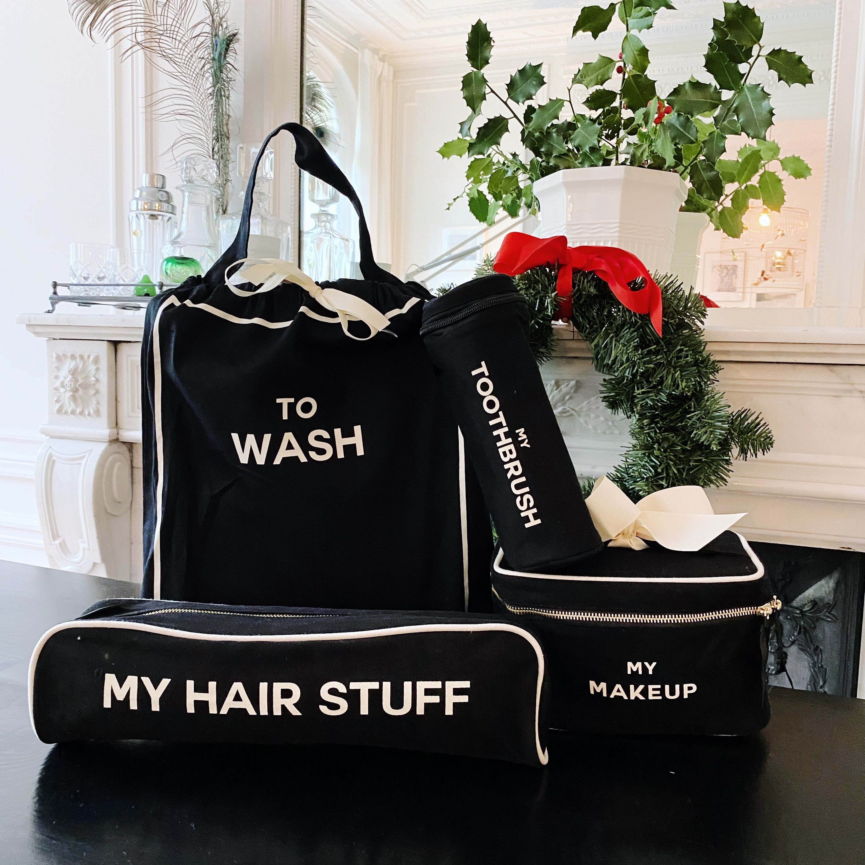 Black Bag-all 4-pack travel set including labeled bags for wash, toothbrush, hair stuff, and makeup on table with holiday decor