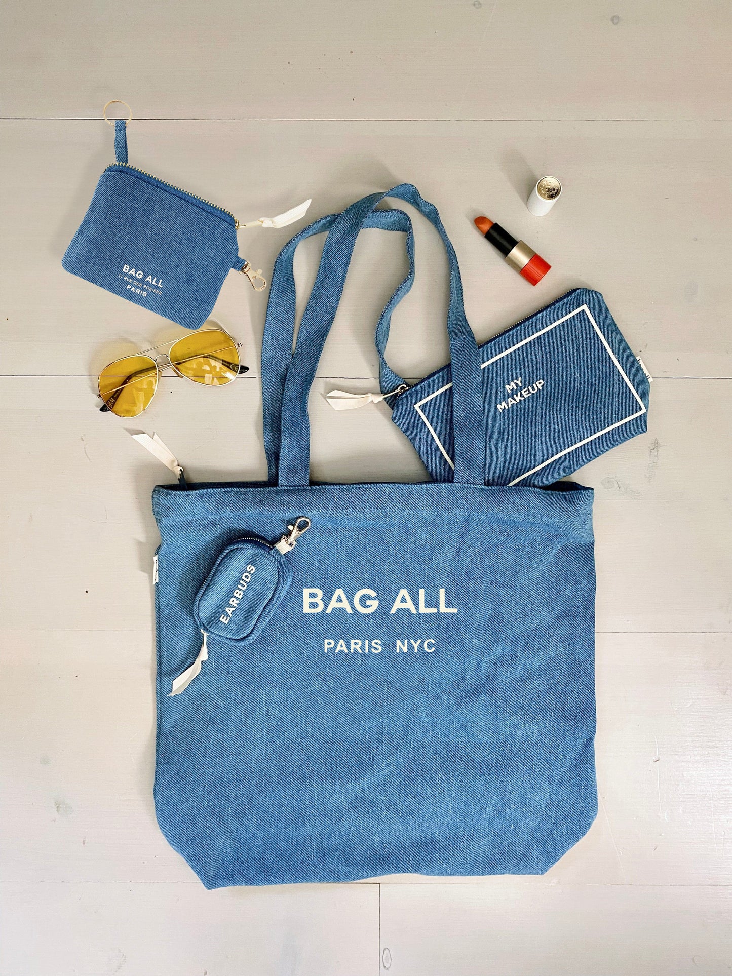 Bag-all Paris Le Marais denim tote bag with zipper and inner pocket, styled with matching accessories including pouch and sunglasses, showcasing versatile everyday design in blue denim