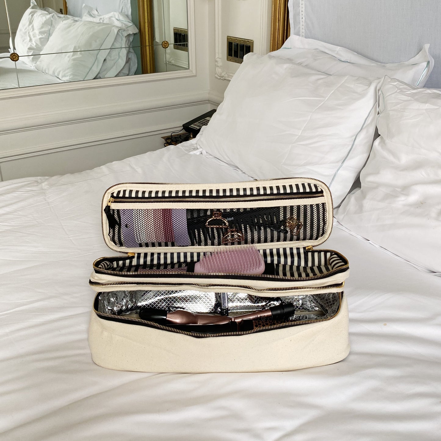 Bag-all Double Hair Tools Travel Case in cream with dual compartments, heat-protective lining, and secure bands for Airwrap accessories, featuring organized storage space on white bedding