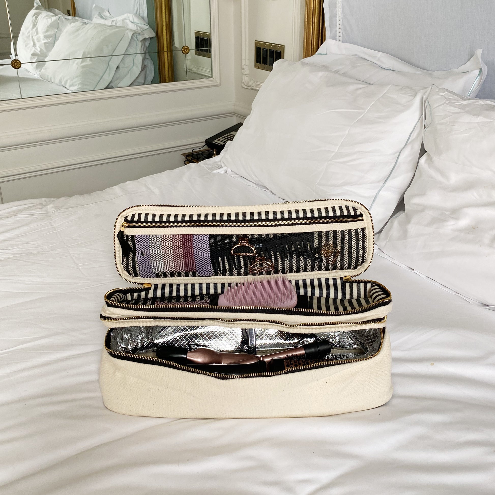 Bag-all Double Hair Tools Travel Case in cream with dual compartments, heat-protective lining, and secure bands for Airwrap accessories, featuring organized storage space on white bedding