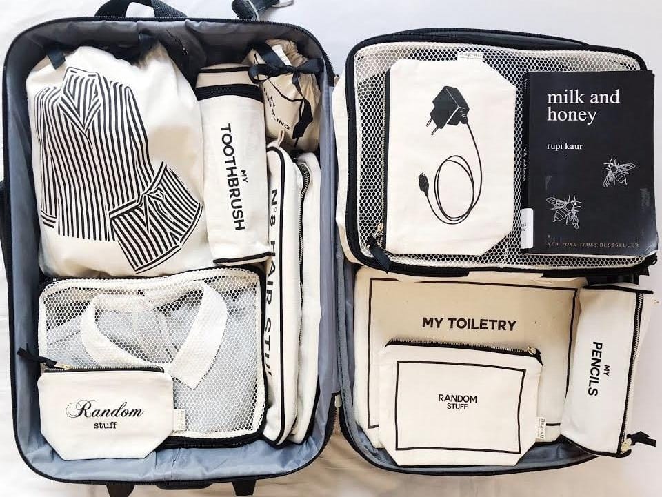 Bag-all Striped Pajamas Travel Bag in cream shown packed in suitcase with organized toiletries and clothing compartments, featuring black and white striped pattern