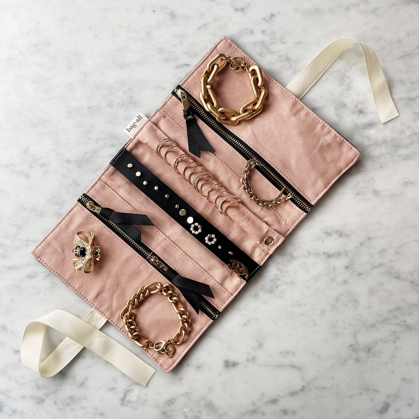 Bag-all Couture Jewelry Roll Medium Black with pink interior, multiple compartments featuring organized jewelry display with gold chain accents, cream ribbon ties for secure closure