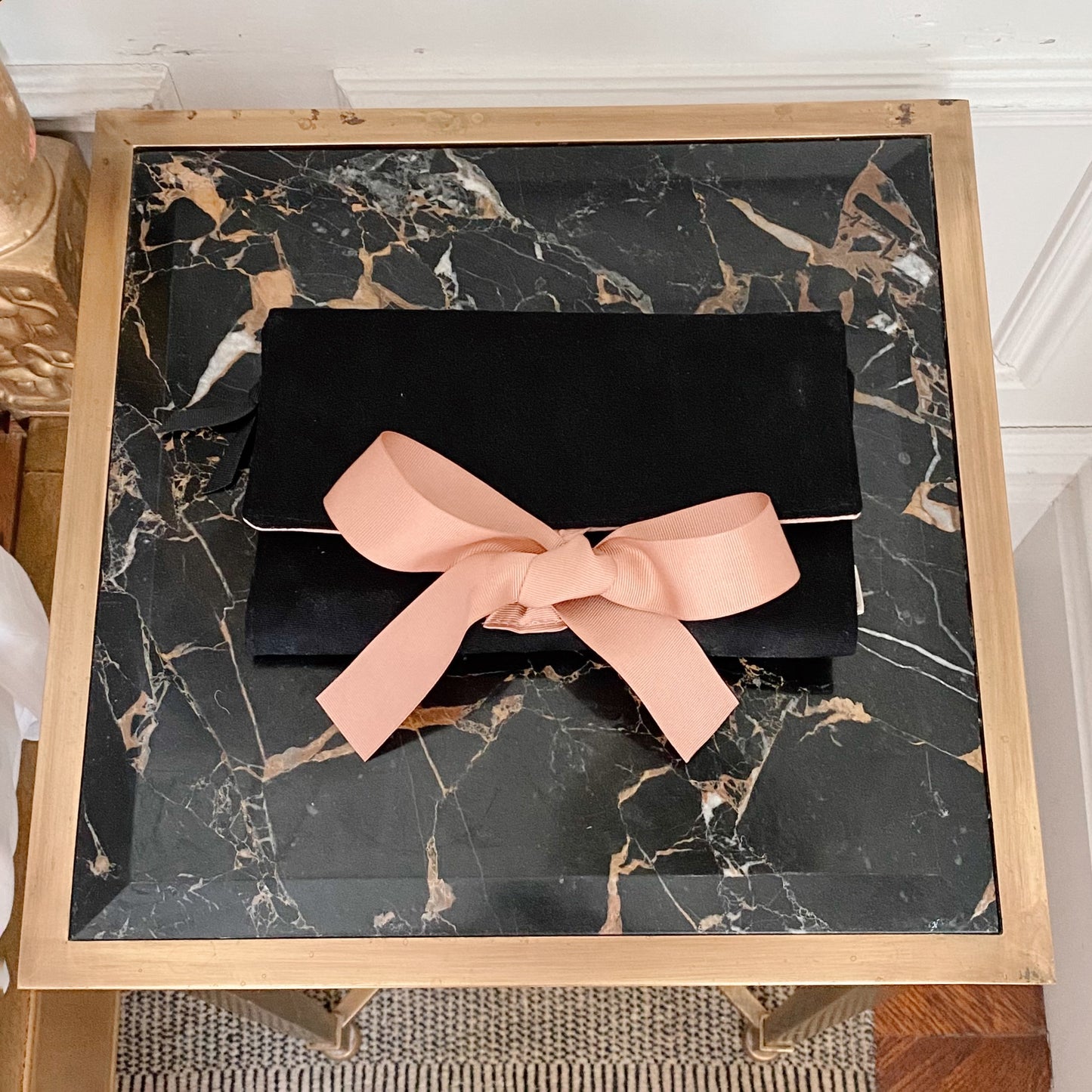 Bag-all Large Jewelry Roll in black with pink bow, elegant travel pouch for storing and organizing jewelry, featuring secure compartments and luxurious design on marble surface