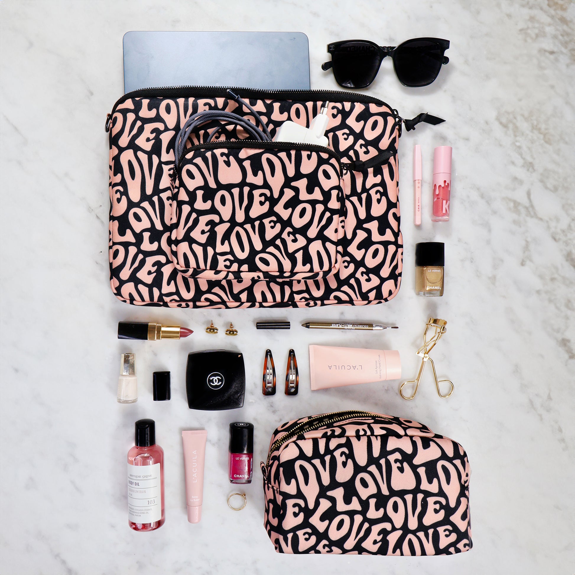 Bag-all Love Pattern Laptop Case with charger pocket, shown with accessories on marble surface. Black and pink love print design, eco-friendly padded protection for 13-inch devices.