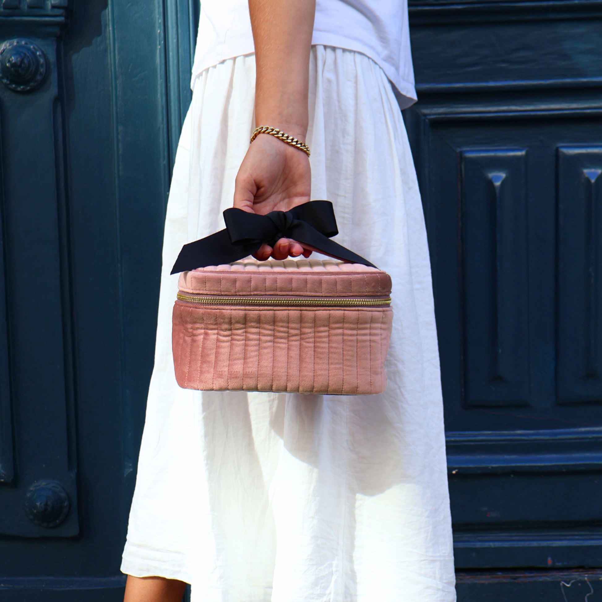 Woman holding pink quilted eco velvet makeup case S with black bow handle by Bag-all outdoors