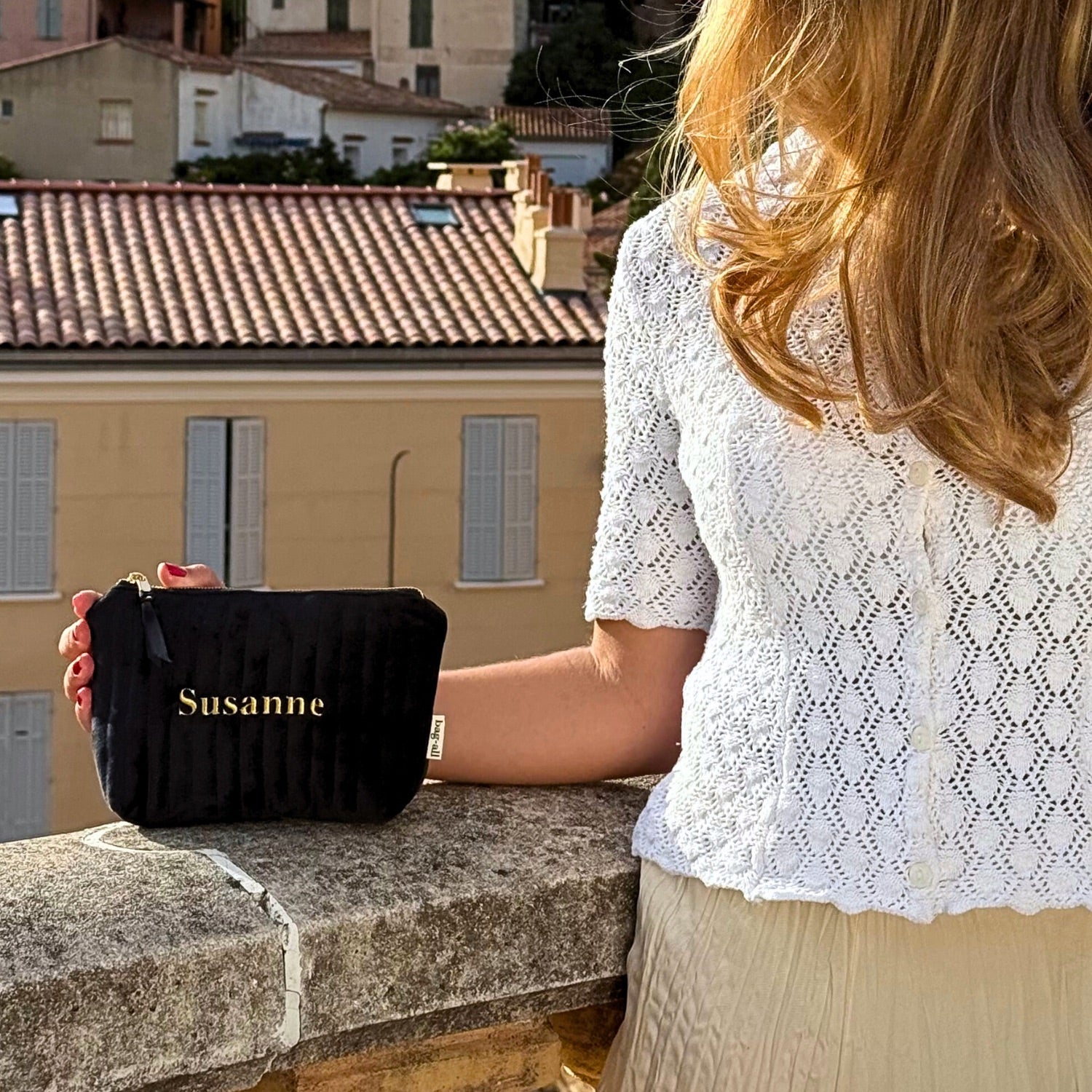 Black quilted eco velvet makeup bag held by woman outdoors personalized with name Susanne Bag-all