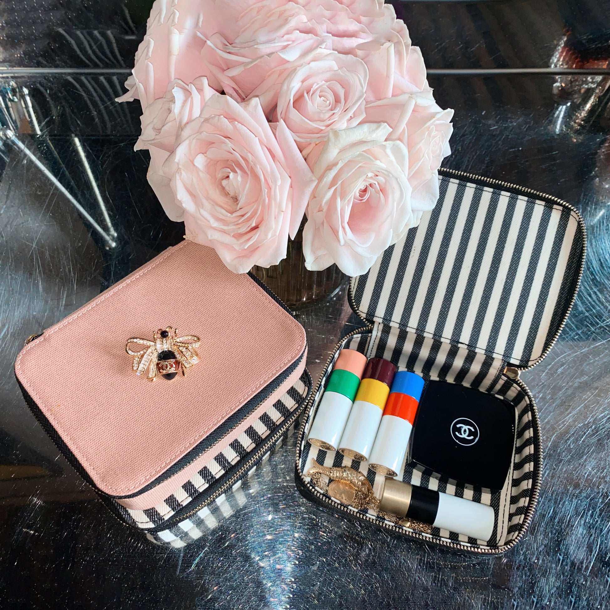 Bag-all pink Cosmetics/Trinket Box with gold bee embellishment, striped lining, and durable zipper, shown with makeup products and blush roses