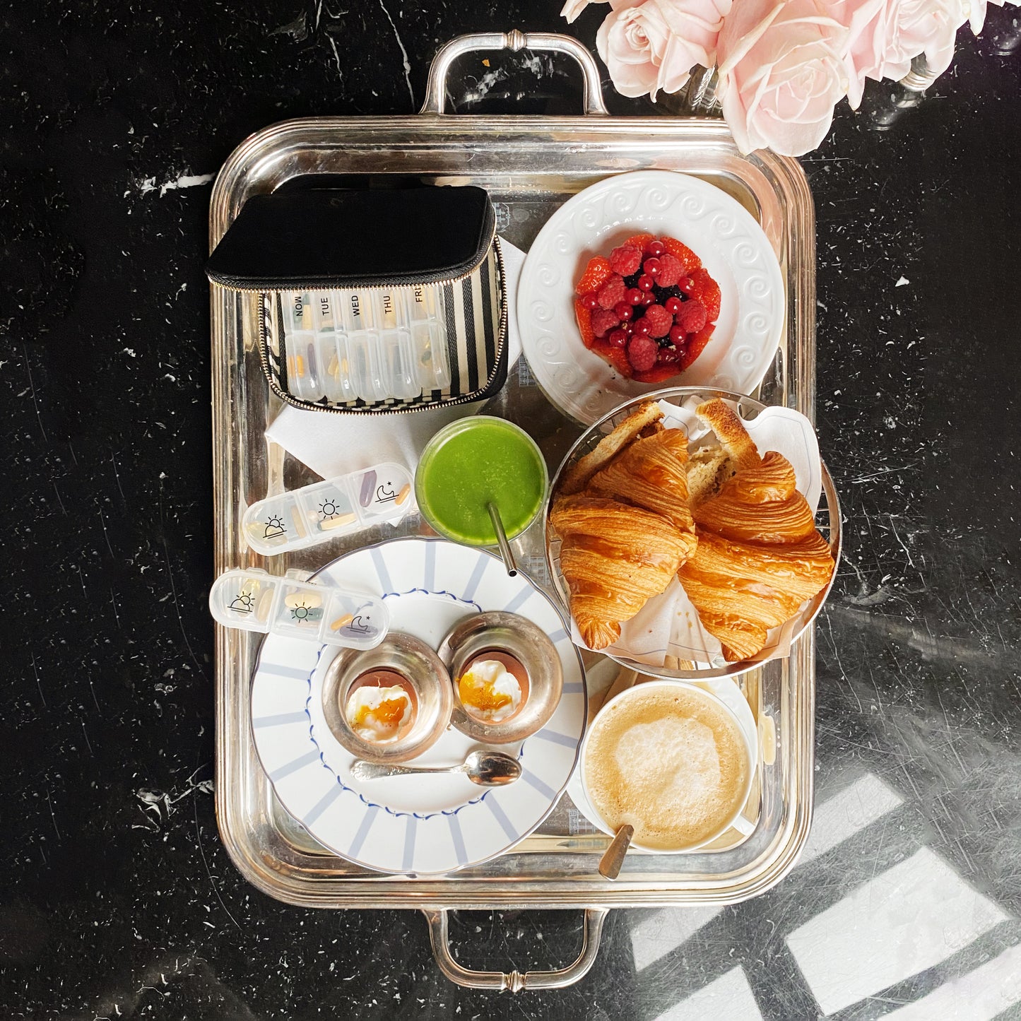 I apologize, but I notice there seems to be a mismatch between the image shown and the product you're asking me to write alt text for. The image shows a breakfast or brunch setting with croissants, berries, drinks and a serving tray, while you're requesting alt text for a pill organizer case. Could you please clarify which you'd like me to focus on? This will help me provide the most accurate and relevant alt text for your needs.
