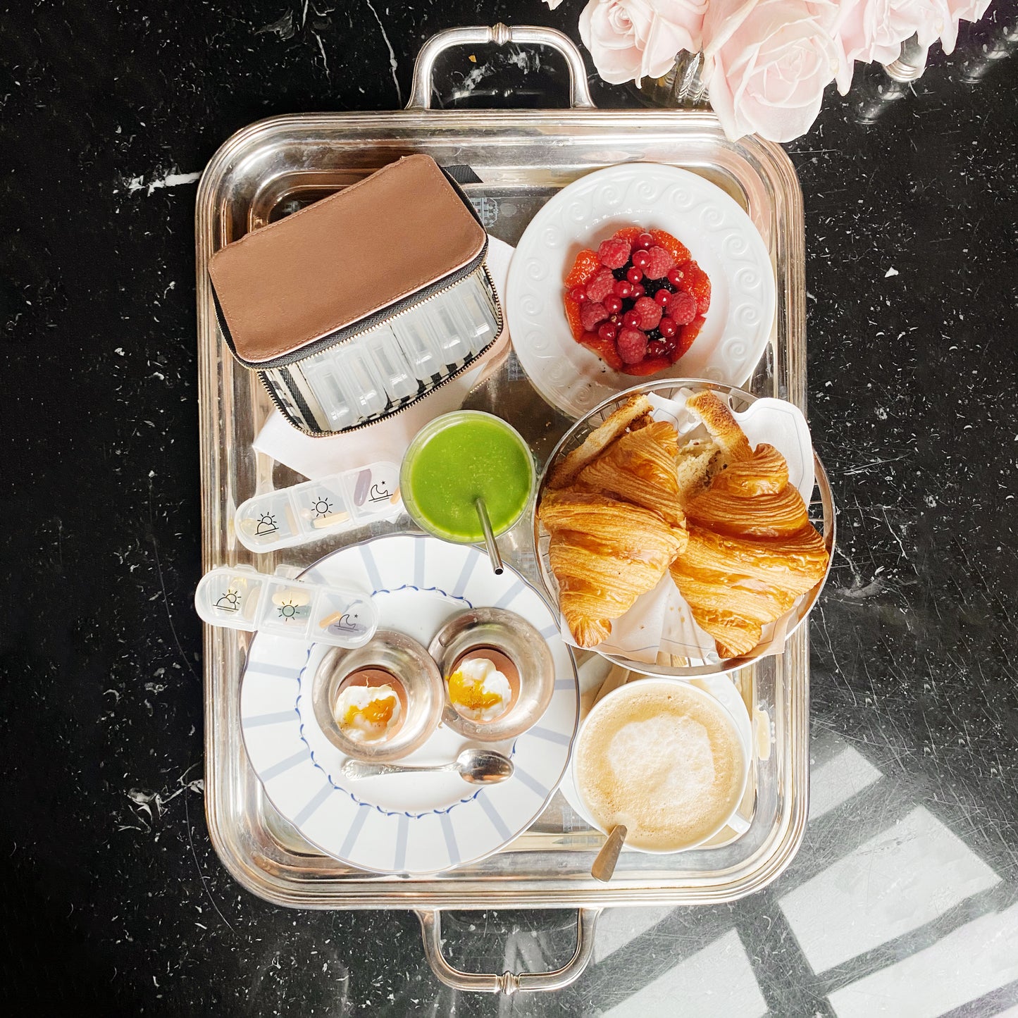This appears to be an unrelated image of a breakfast or brunch setting on a silver tray, showing pastries, beverages and other food items. For the pill case product you described, I'll create an appropriate ALT text:
Bag-all Large Pill Travel Case in pink cotton with daily organizer compartments, zipper closure for secure medication storage, perfect for travel and daily use
