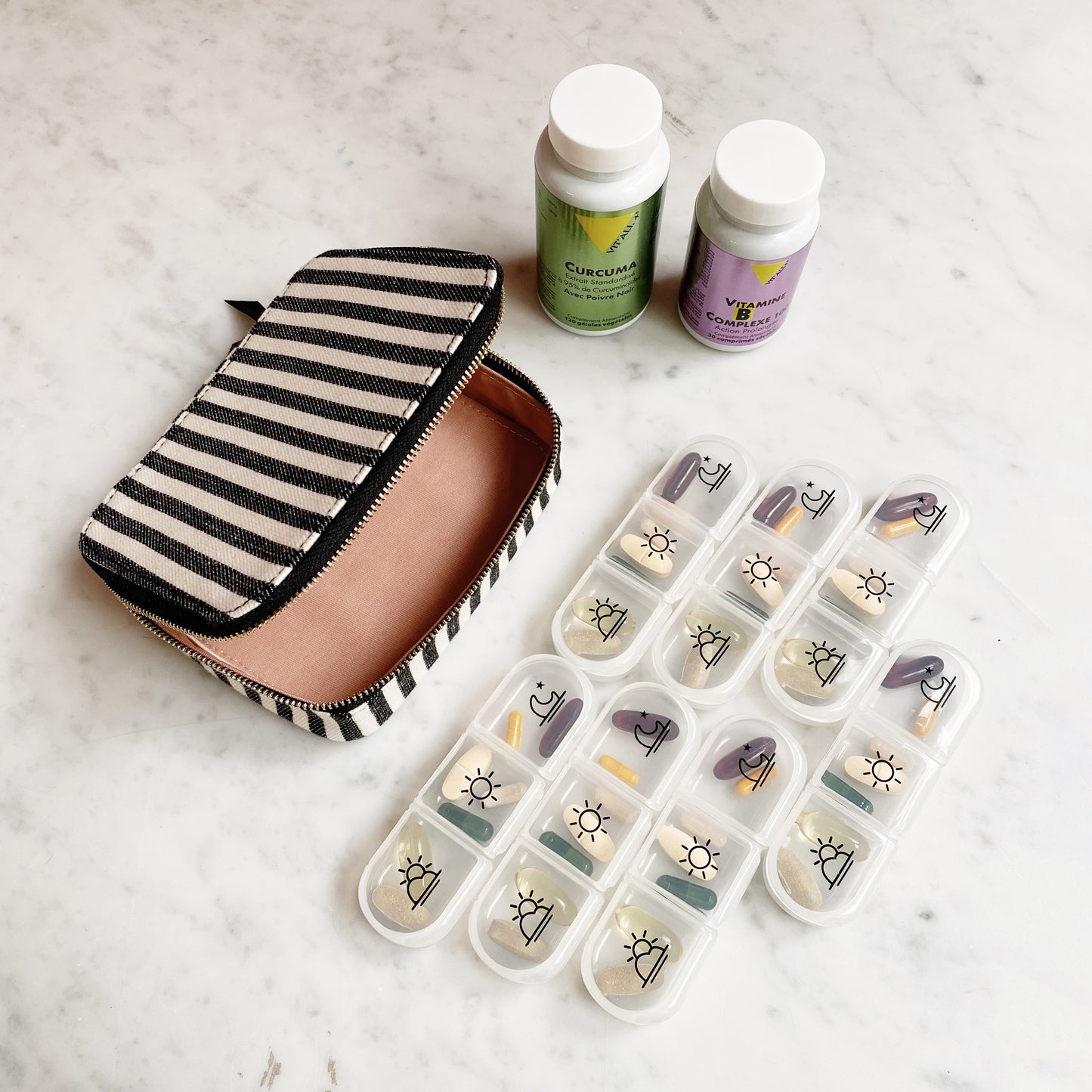 Bag-all Large Pill Travel Case with striped cotton exterior, daily organizer compartments, zipper closure, shown with medicine bottles and pill containers on marble surface.