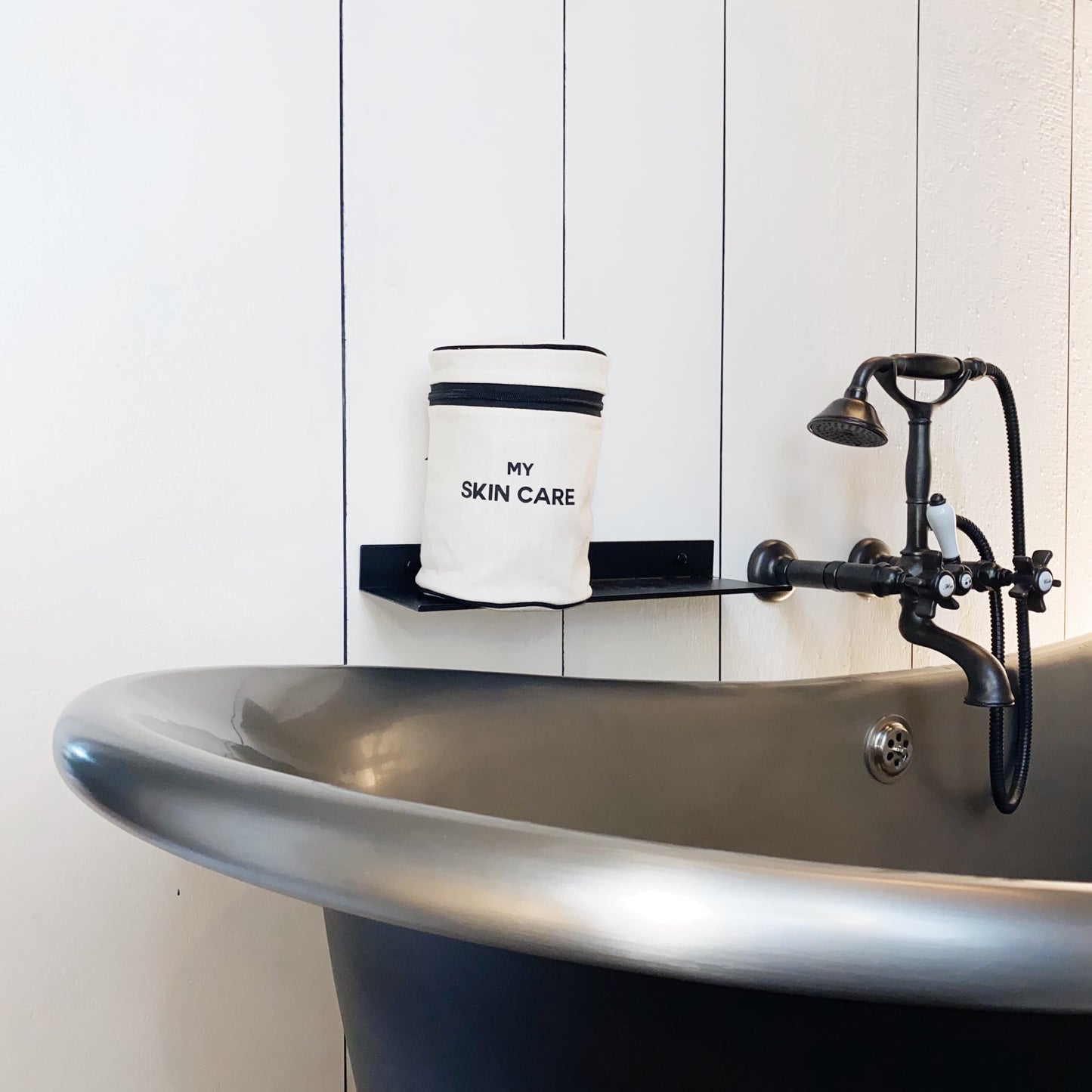 Bag-all Round My Skin Care Case in cream displayed on vintage bathtub edge, featuring black text and trim, perfect for organized skincare storage
