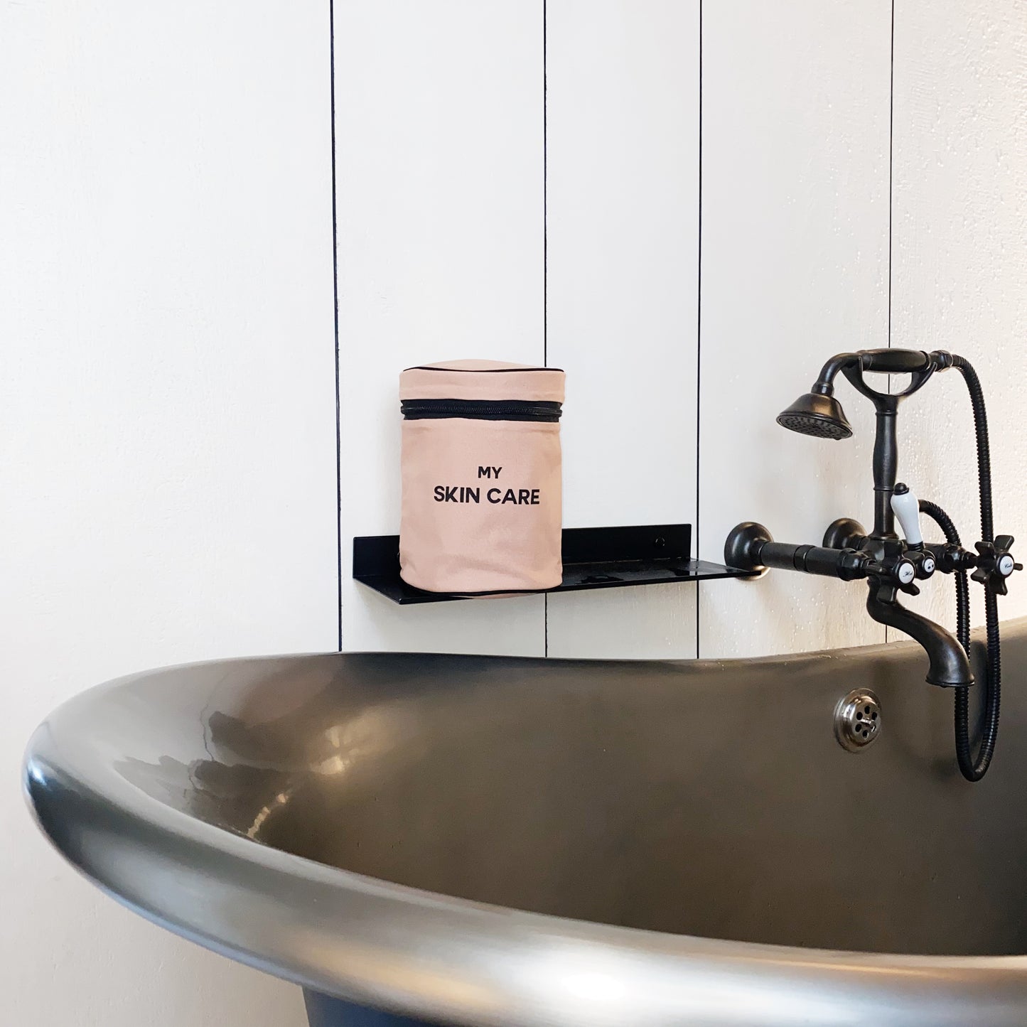 Bag-all Round My Skin Care Case in pink/blush displayed on vintage bathroom shelf near elegant pedestal sink with antique faucet, showcasing stylish bathroom organization