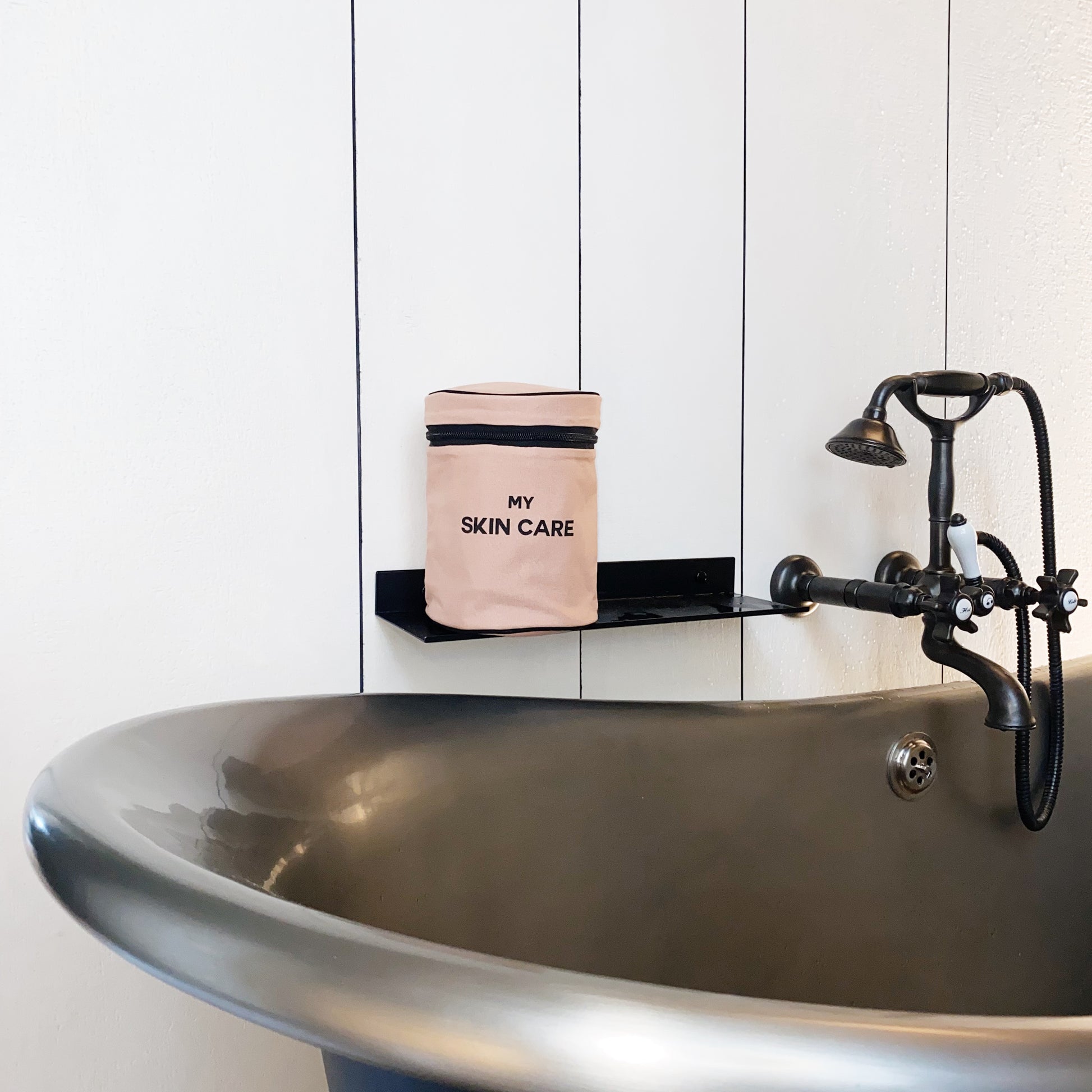 Bag-all Round My Skin Care Case in pink/blush displayed on vintage bathroom shelf near elegant pedestal sink with antique faucet, showcasing stylish bathroom organization