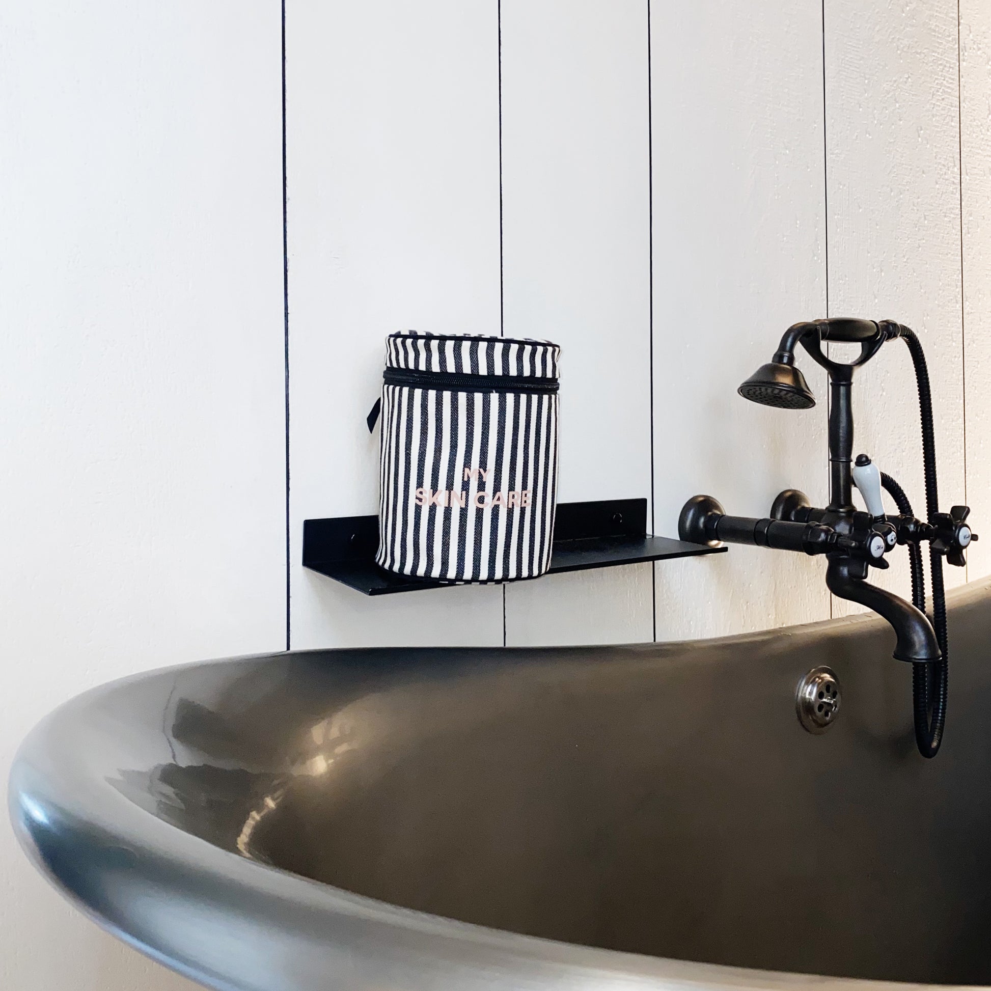 Bag-all Round My Skin Care Case Striped - stylish black and white striped cylindrical organizer displayed on bathroom shelf near vintage faucet, perfect for skincare storage