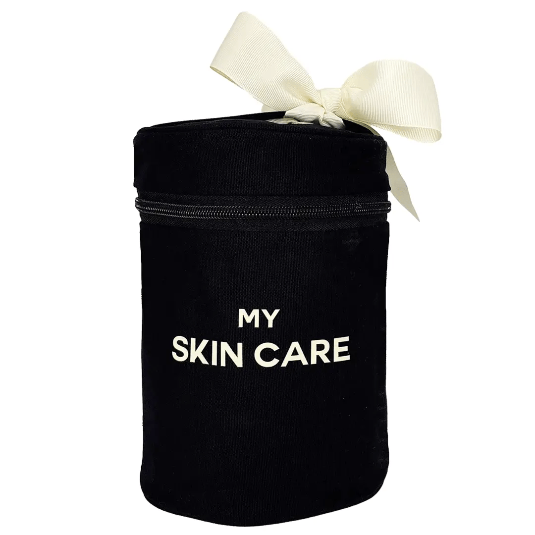Bag-all Round Skin Care Case with Handle in black cotton featuring cream bow, white text "MY SKIN CARE", laminated interior with organizing pockets for beauty products