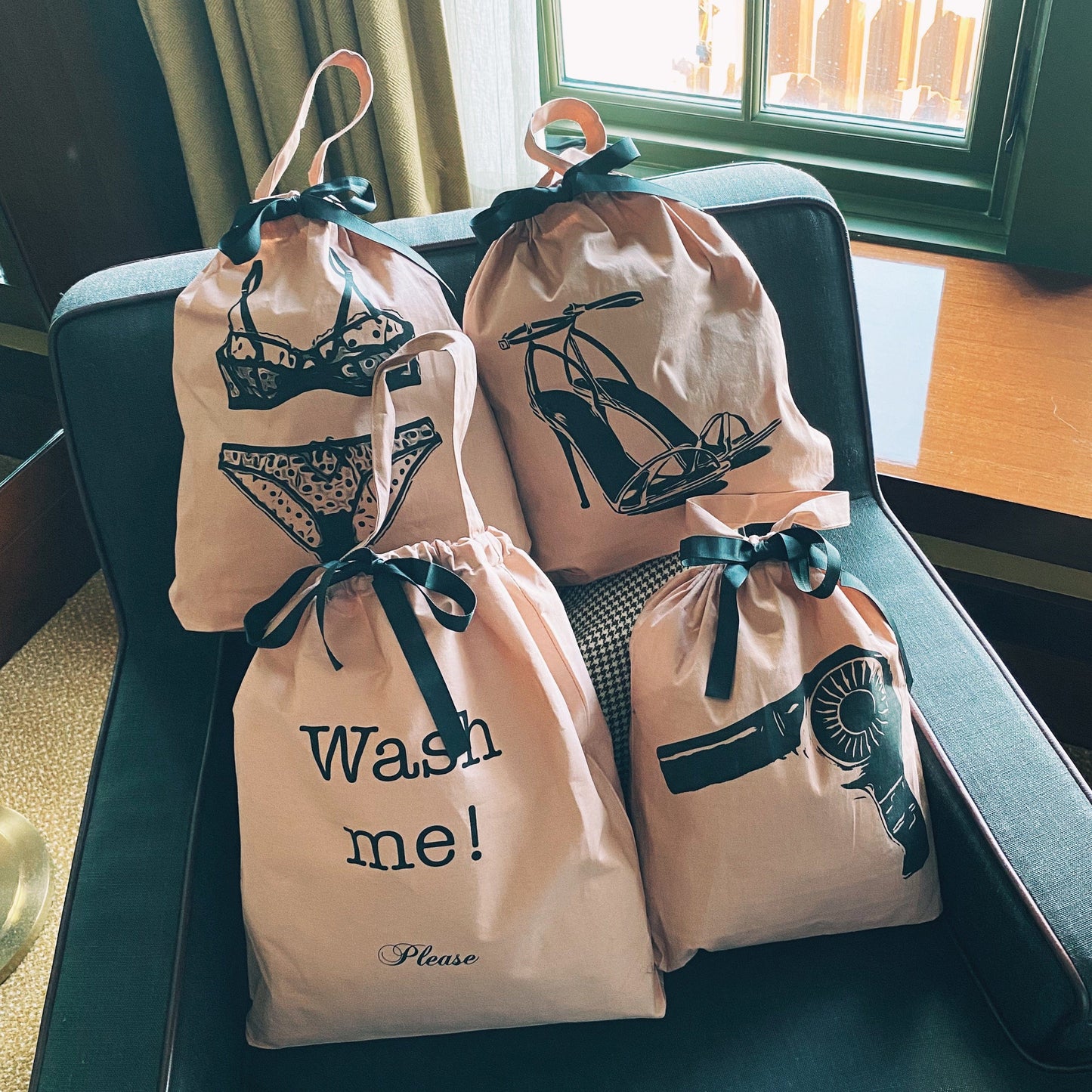 Bag-all Women's Travel Set 4-pack in Pink/Blush featuring organizing bags for laundry, hair dryer, lingerie, and shoes with black bow details and stylish graphic prints