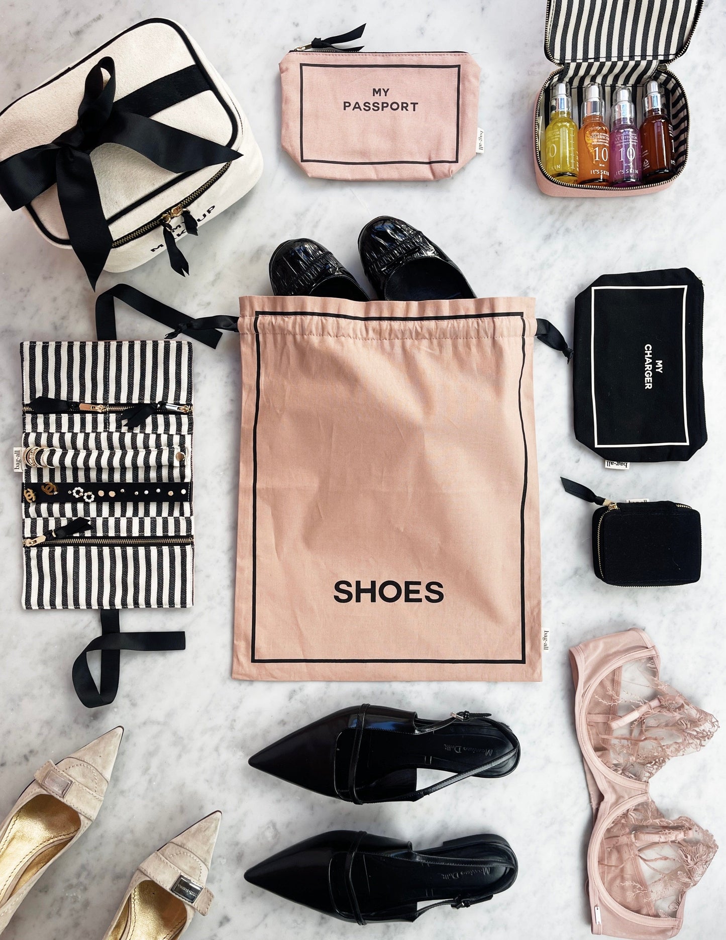 Bag-all Toiletry Travel Gift Set 4-Pack in pink featuring organized travel essentials: cotton toiletry pouch, passport case, shoe bag, and striped cosmetic organizer with bottles on marble surface