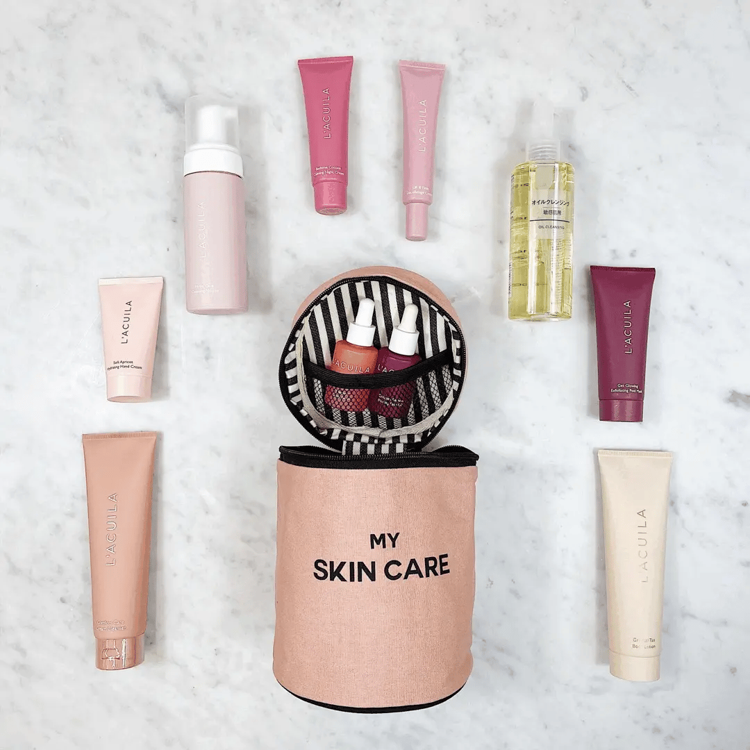 Bag-all Round Skin Care Case with Handle in Pink/Blush shown with beauty products, featuring striped interior lining, mesh pocket, and organized skincare essentials on marble surface