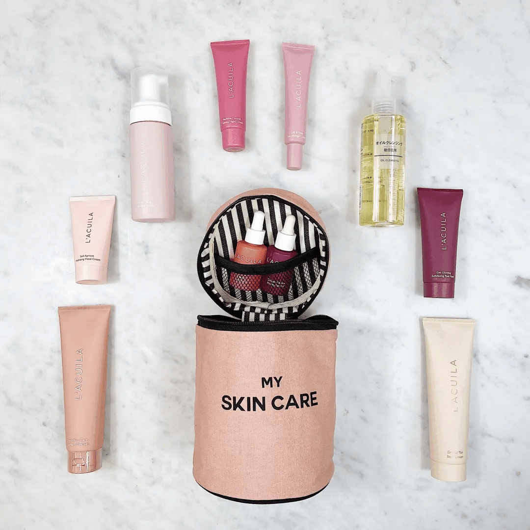 Bag-all Round Skin Care Case with Handle in Pink/Blush shown with beauty products, featuring striped interior lining, mesh pocket, and organized skincare essentials on marble surface