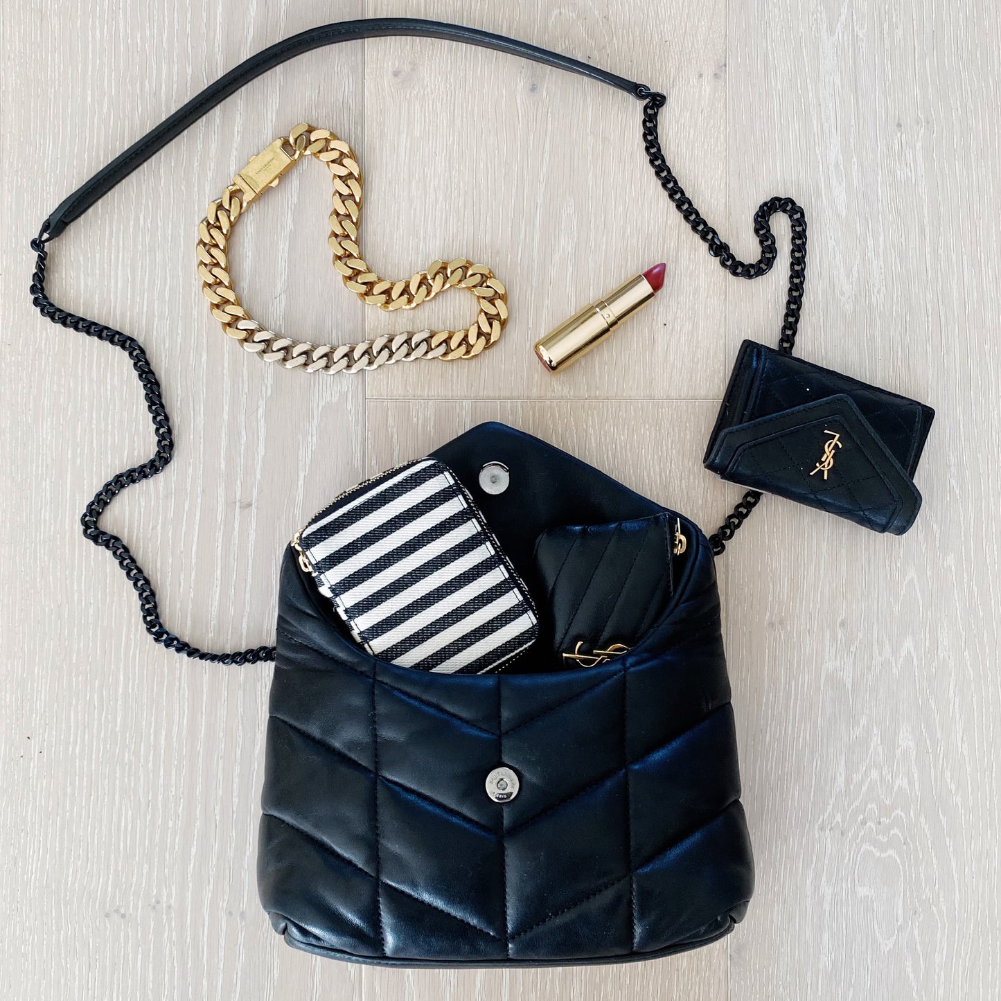 Bag-all Jewelry/Trinket Box with striped design shown inside stylish black quilted handbag, alongside gold chain bracelet and lipstick on light wooden surface