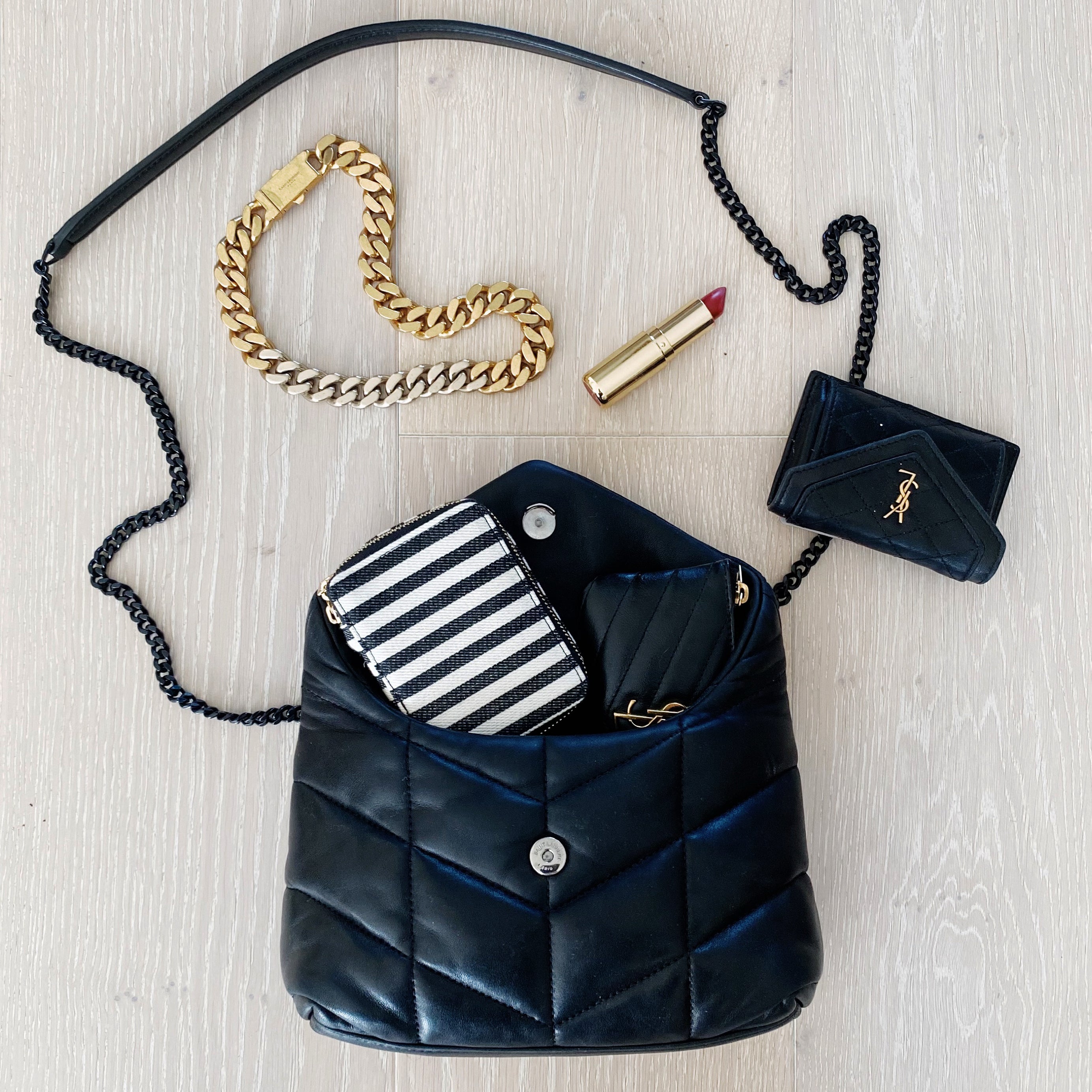 Bag-all Jewelry/Trinket Box with striped design shown inside stylish black quilted handbag, alongside gold chain bracelet and lipstick on light wooden surface