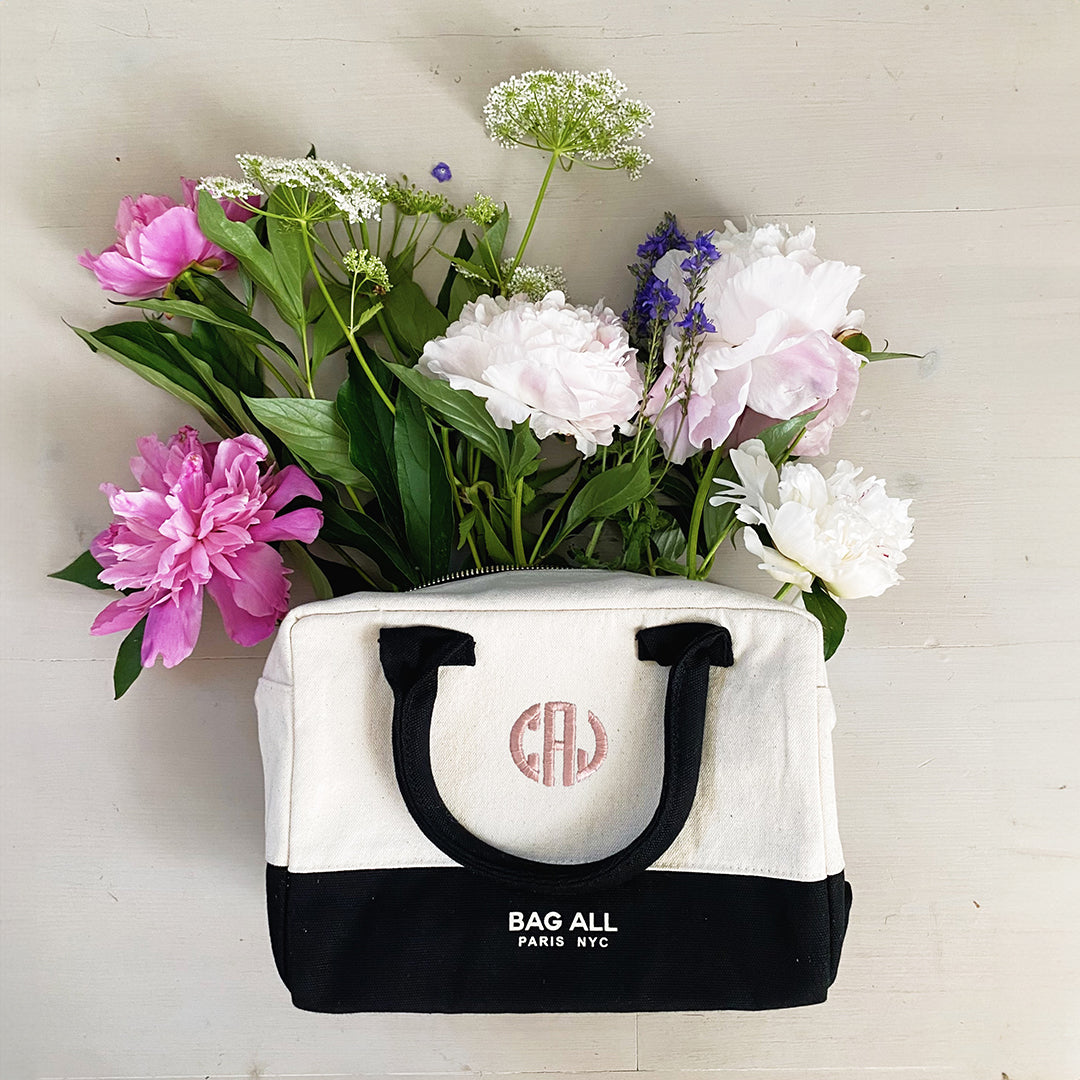 Bag-all Stylish Monogram Lunch Box in cream and black with custom monogram, featuring pink and white peonies and delicate white flowers arranged inside, showcasing its versatile use as both storage and display