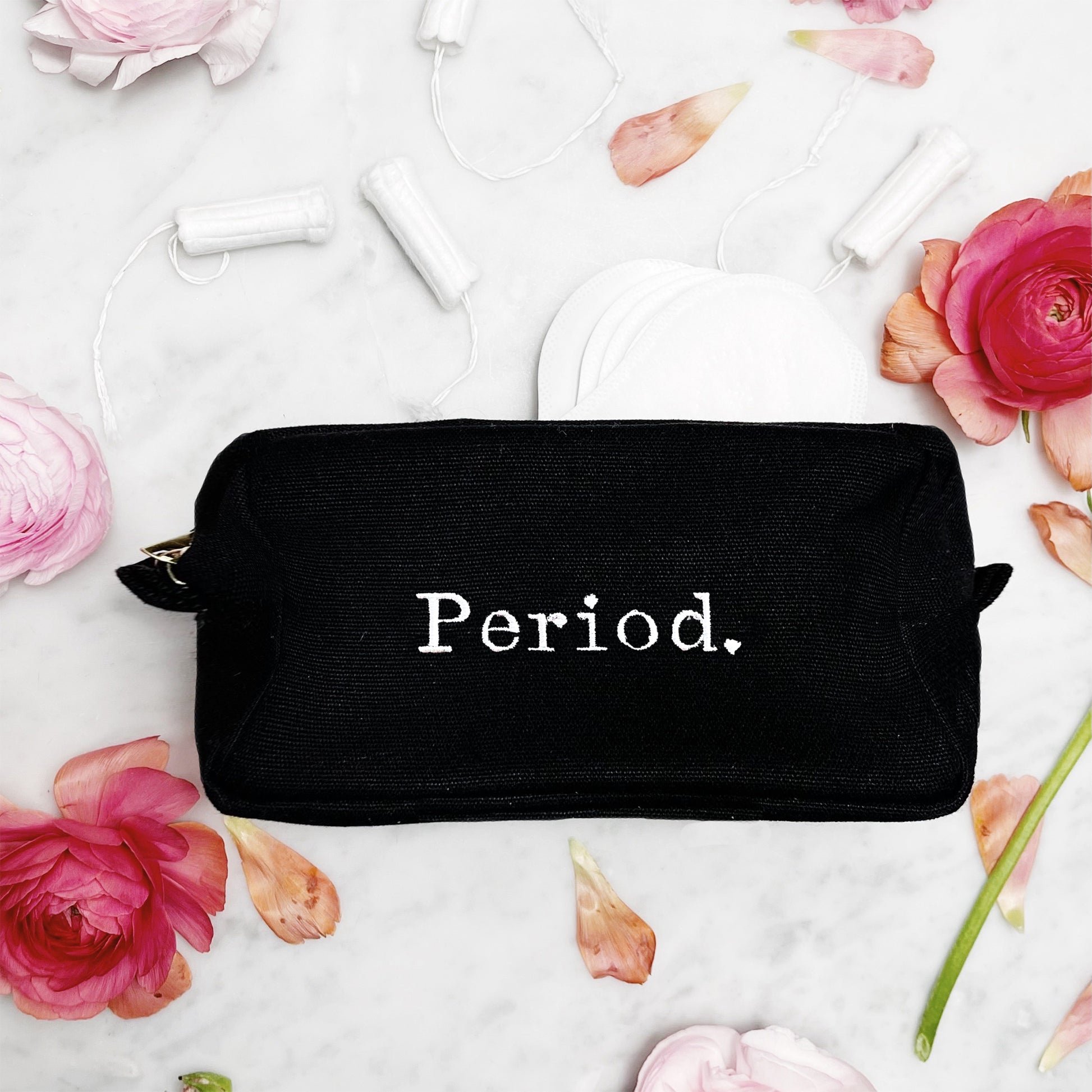 Bag-all Stylish Sanitary Pouch in black canvas with white 'Period.' embroidery, surrounded by pink roses and feminine essentials on white background