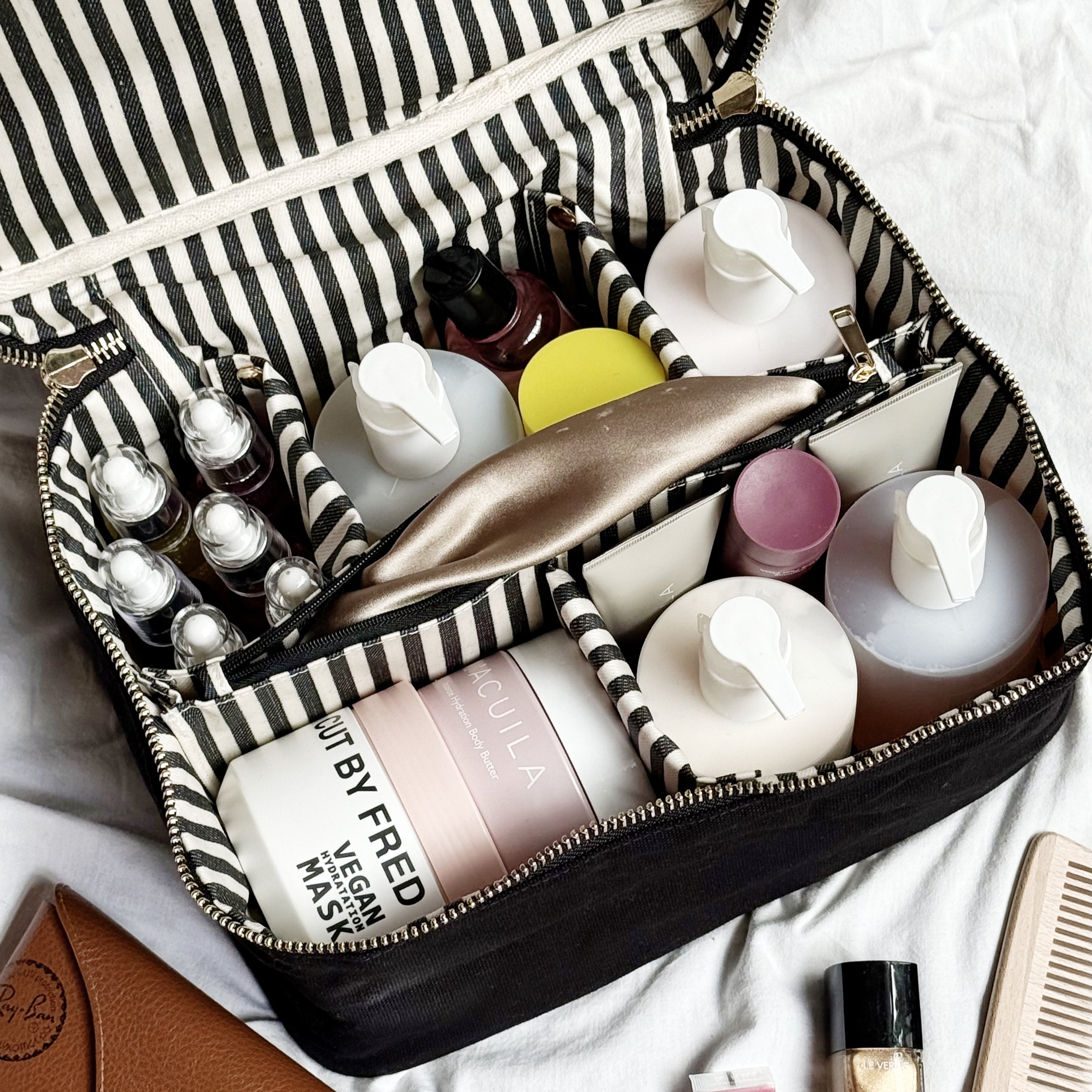 Large black Bag-all vanity case with striped organizer insert holding skincare and makeup containers neatly arranged.