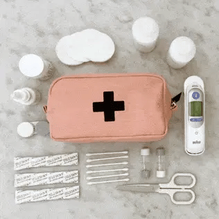Bag-all First Aid Organizing Pouch in blush pink with medical supplies including bandages, scissors, thermometer and medicine containers on grey surface