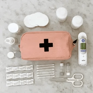 Bag-all First Aid Organizing Pouch in blush pink with medical supplies including bandages, scissors, thermometer and medicine containers on grey surface