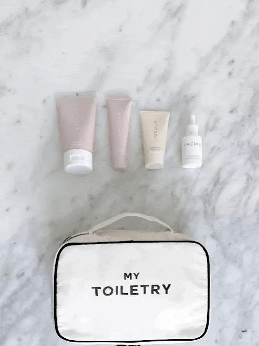 Bag-all Folding/Hanging Toiletry Case in cream with 'My Toiletry' text, displayed with pink and neutral skincare products on marble surface, showcasing organized travel storage