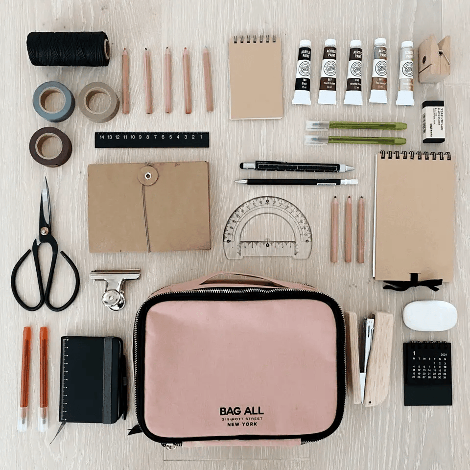 Bag-all Weekend Packing Set 3-Pack in Pink/Blush shown with art supplies, featuring double-sided packing cube, multi-use case and pill organizer in natural cotton, arranged in flat lay composition
