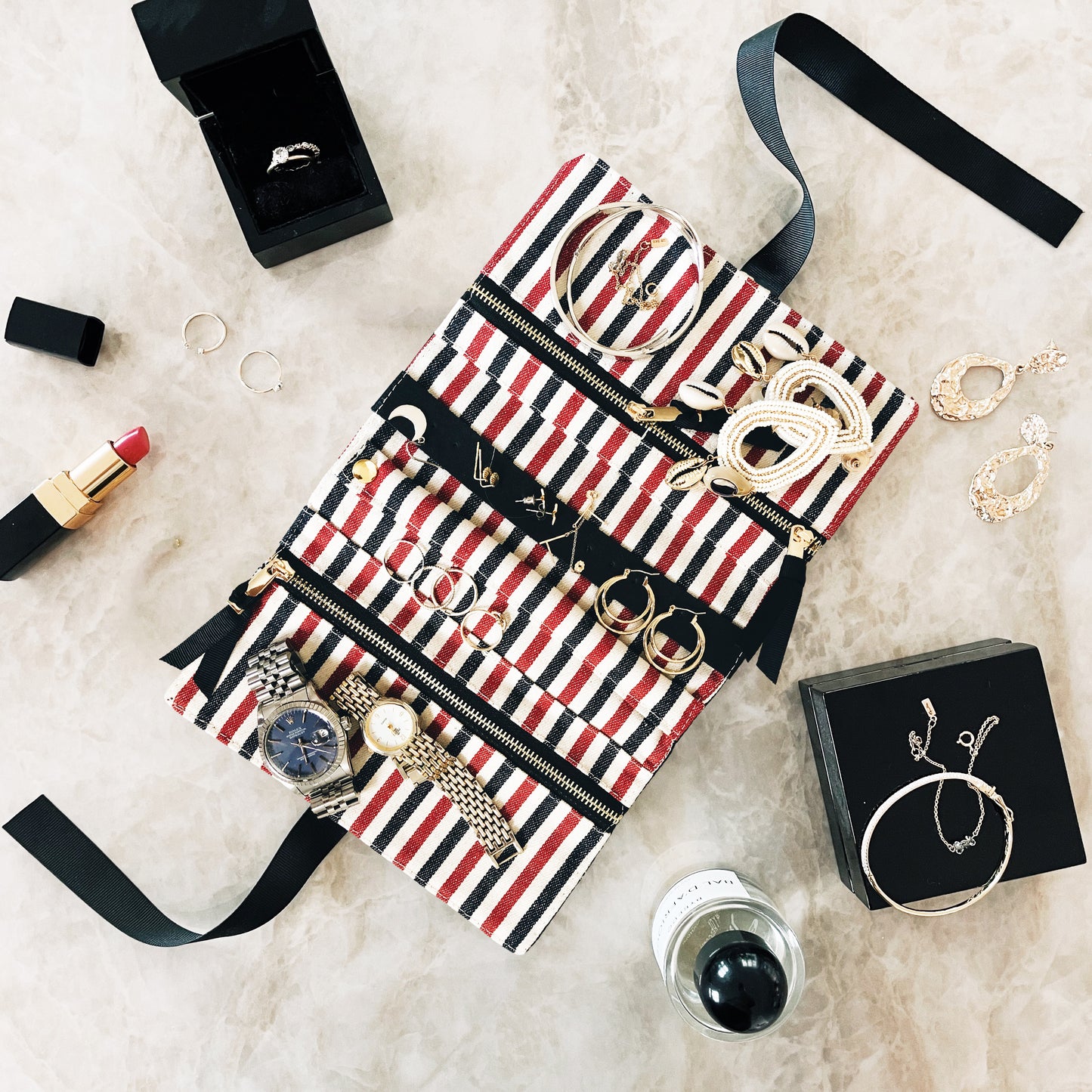 Bag-all Jewelry Organizer Travel Pouch in cream with blue-red-white pattern, featuring multiple compartments, leather earring holder, and ring storage displayed with jewelry accessories