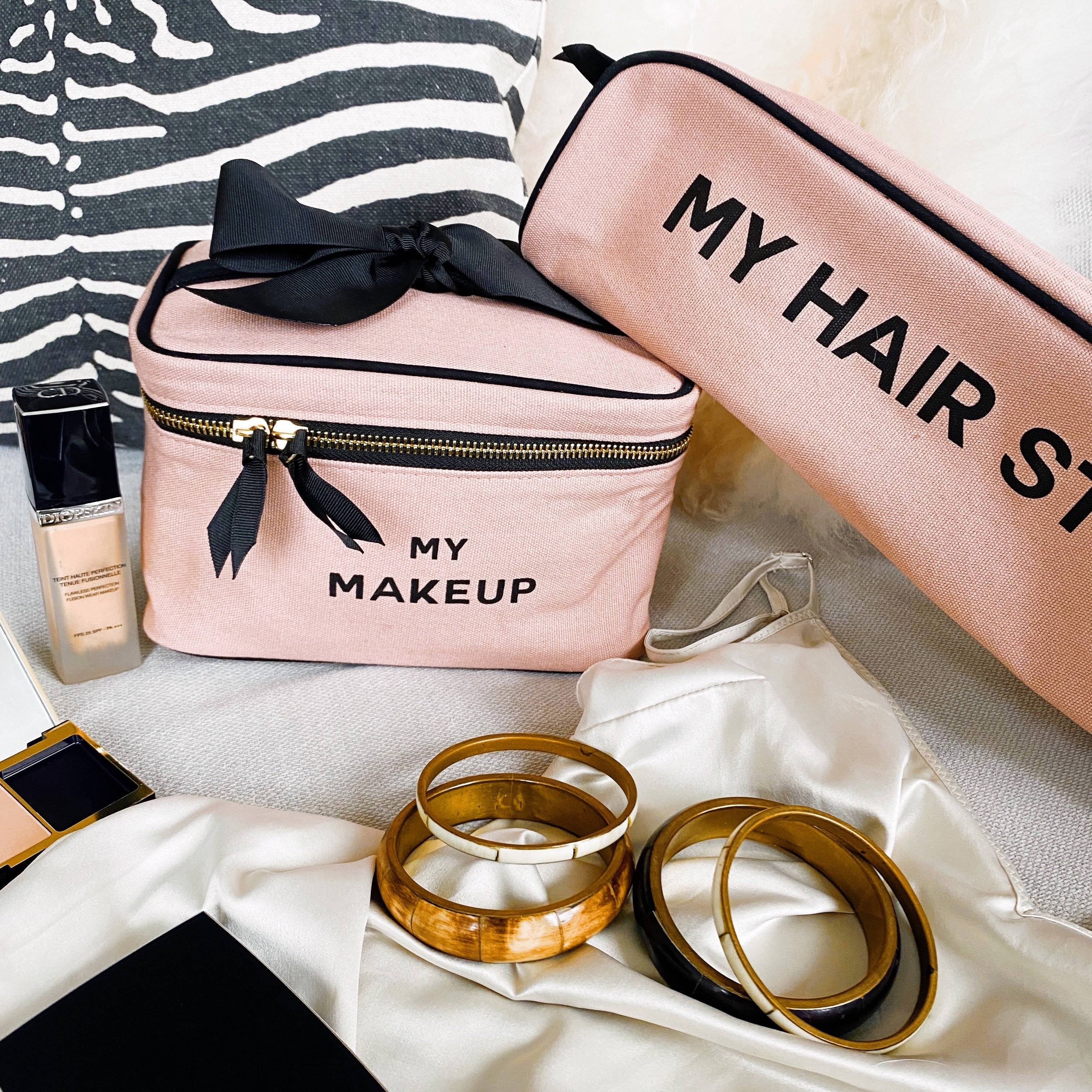 Bag-all Hair Stuff Travel Case in blush pink with black bow detail and gold zipper, shown alongside matching makeup case. Heat-resistant thermal lined organizer for styling tools and accessories.