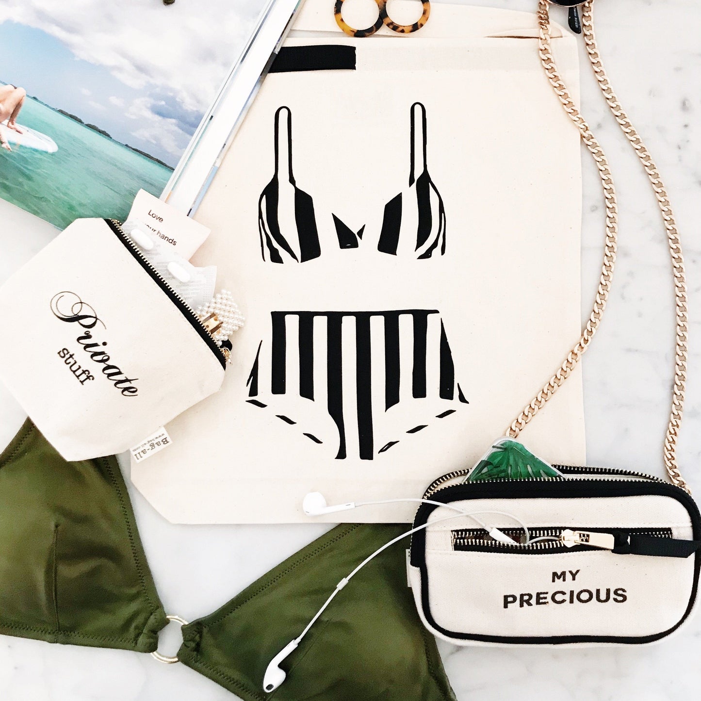 Bag-all My Precious organizing bag with black and white striped bikini print, featuring stylish chain strap and zipper compartments for travel essentials