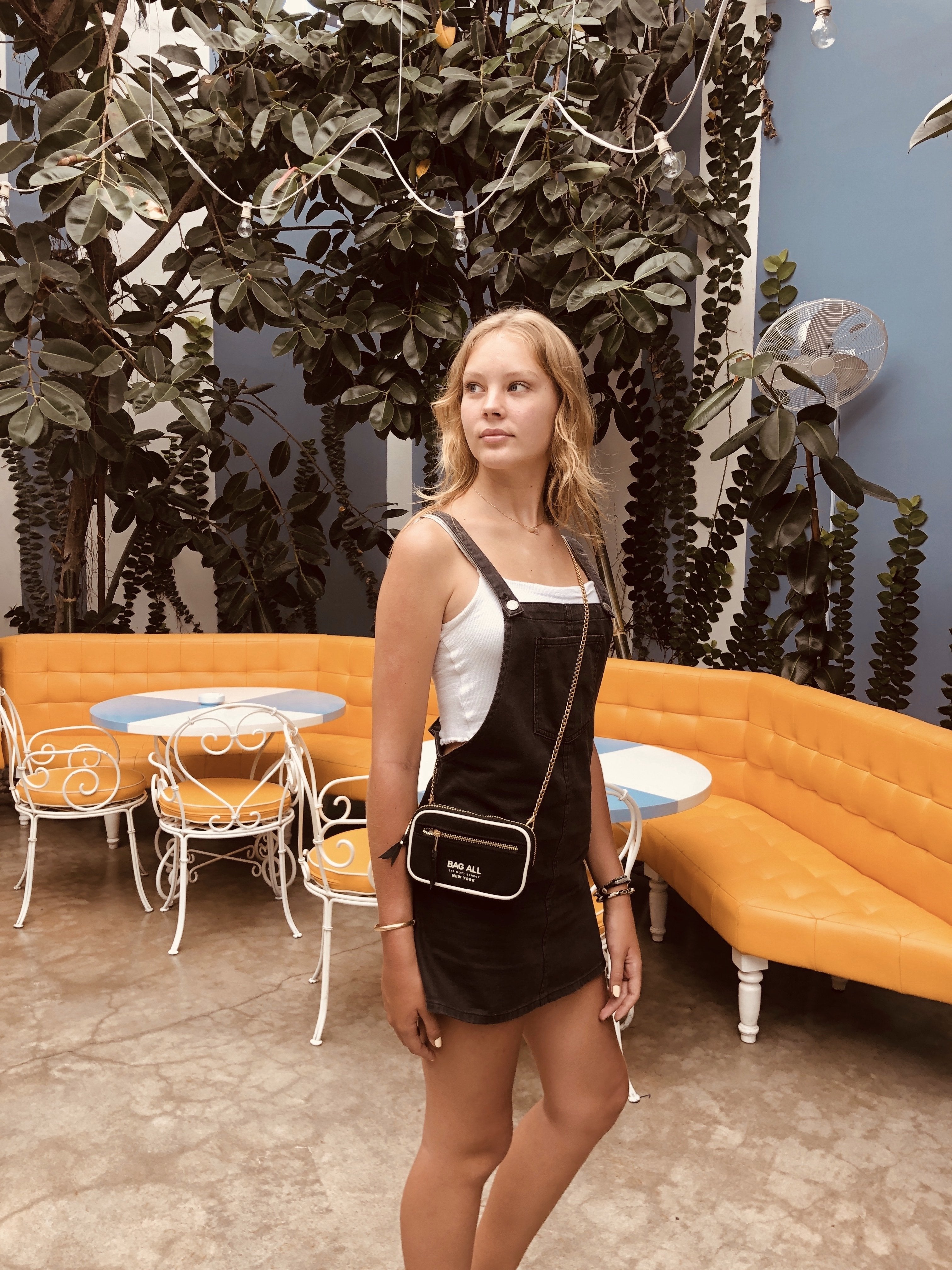 Bag-all Gold Chain strap shown in outdoor cafe setting with orange seating, versatile accessory for computer cases, adjustable and reusable metal chain design
