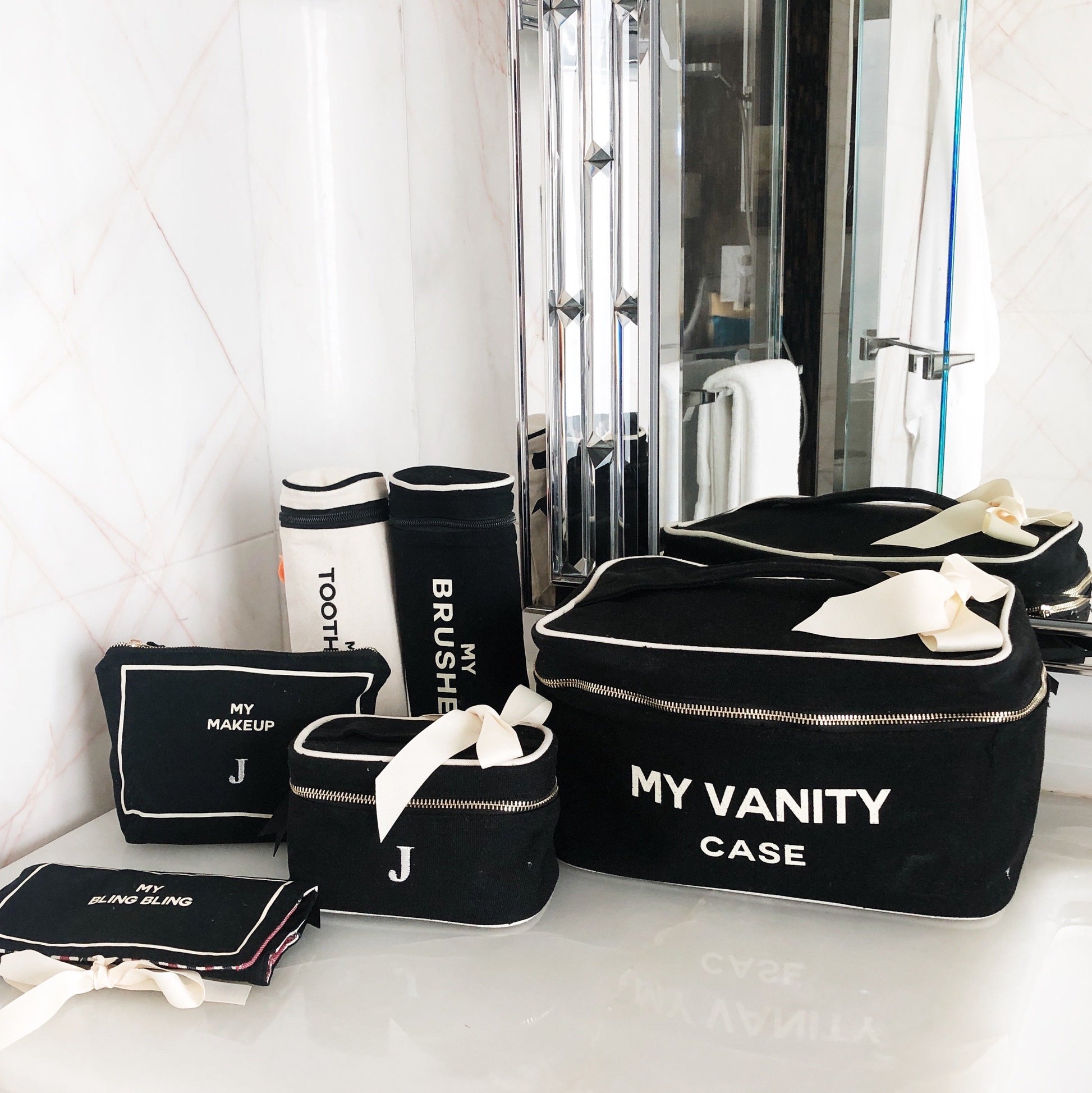 Bag-all My Vanity Case collection featuring black and white travel organizers with personalized monogram, elegant bow details, and matching accessories for stylish organization