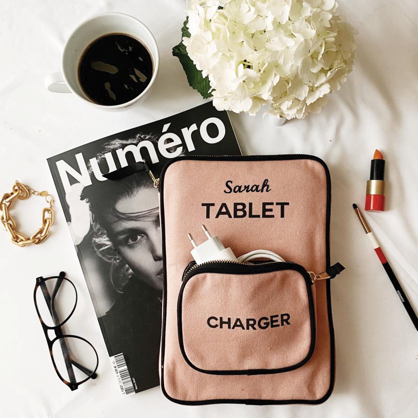 Bag-all Tablet Case 11" in blush pink with charger pocket and personalized name, styled with magazine, coffee, hydrangeas, glasses and lipstick on white surface