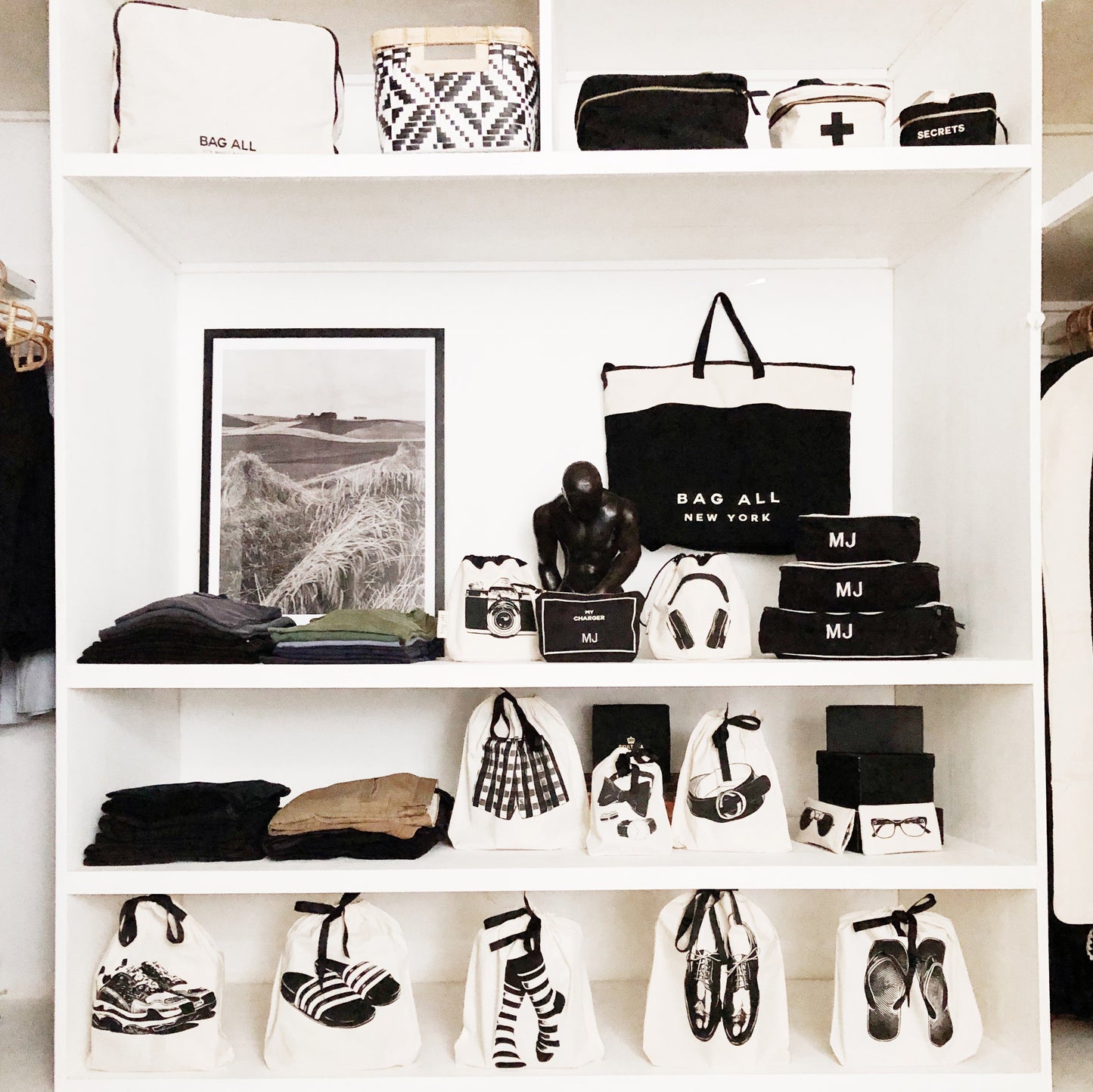 Bag-all Flip Flops Shoe Bag in cream, displayed on white shelving unit alongside collection of organized shoe bags, storage solutions, and travel accessories in black and white aesthetic