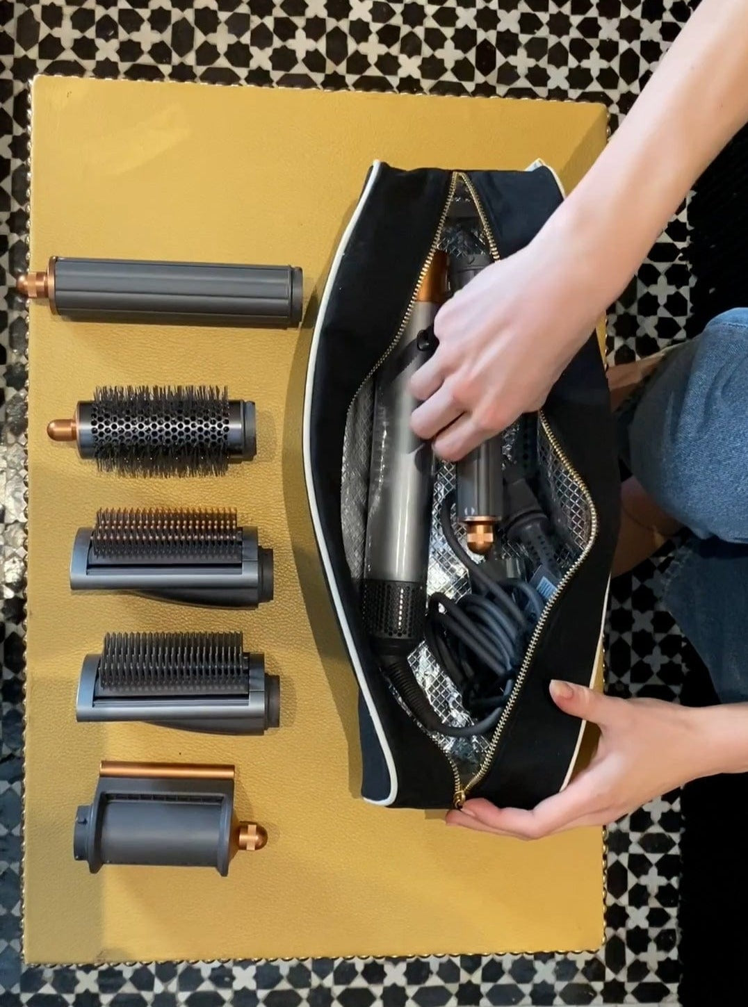 Bag-all Roomy Hair Wrap Tools Travel Case in black with heat-resistant lining, shown with Dyson Airwrap attachments and styling tools, featuring gold zipper and sustainable cotton material