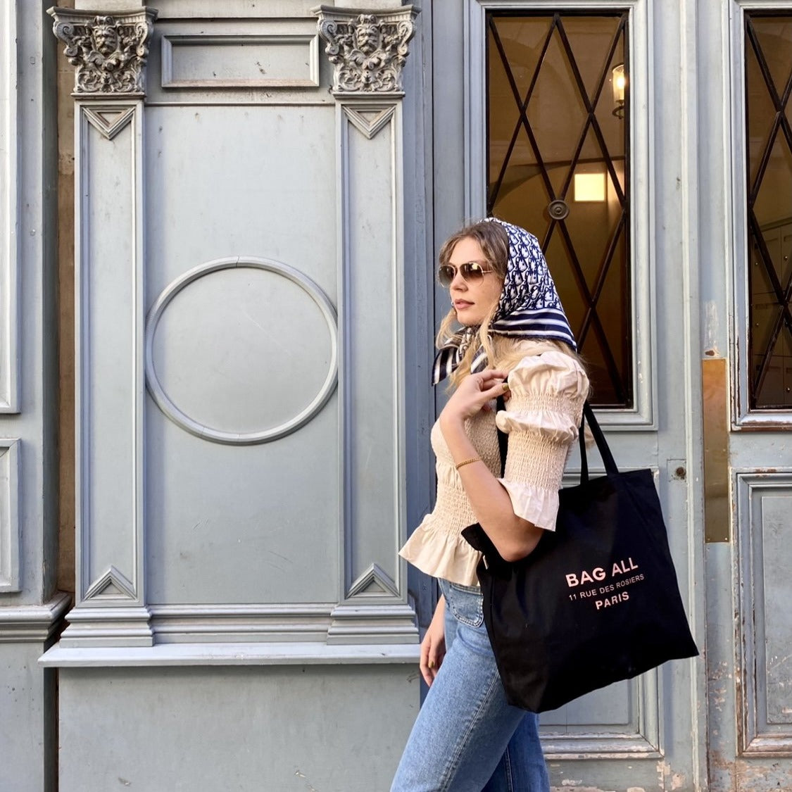 Une fille dans un foulard tenant un sac fourre-tout noir à fermeture éclair.