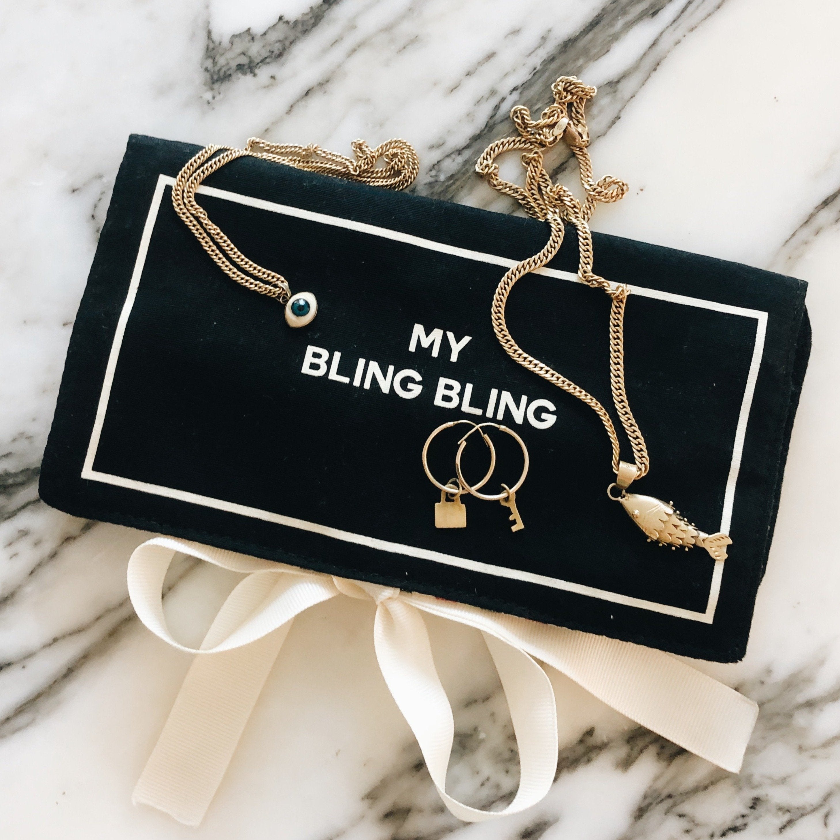 Bag-all black Jewelry Organizer Travel Pouch with three compartments, leather earring holder and ring storage, featuring gold chain and 'My Bling Bling' text on elegant marble background