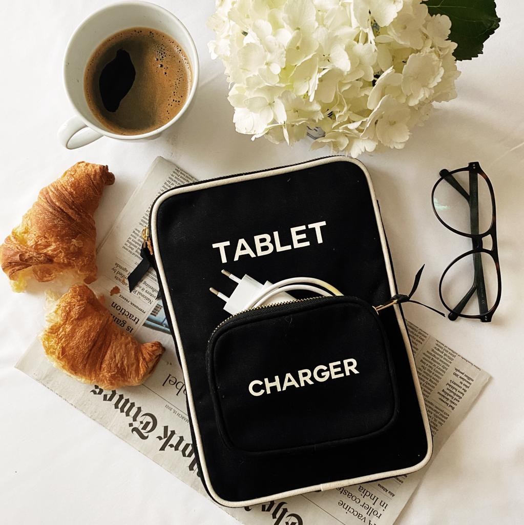Bag-all black tablet case with charger pocket styled with coffee, croissants and white hydrangeas, showcasing sleek design and practical storage features