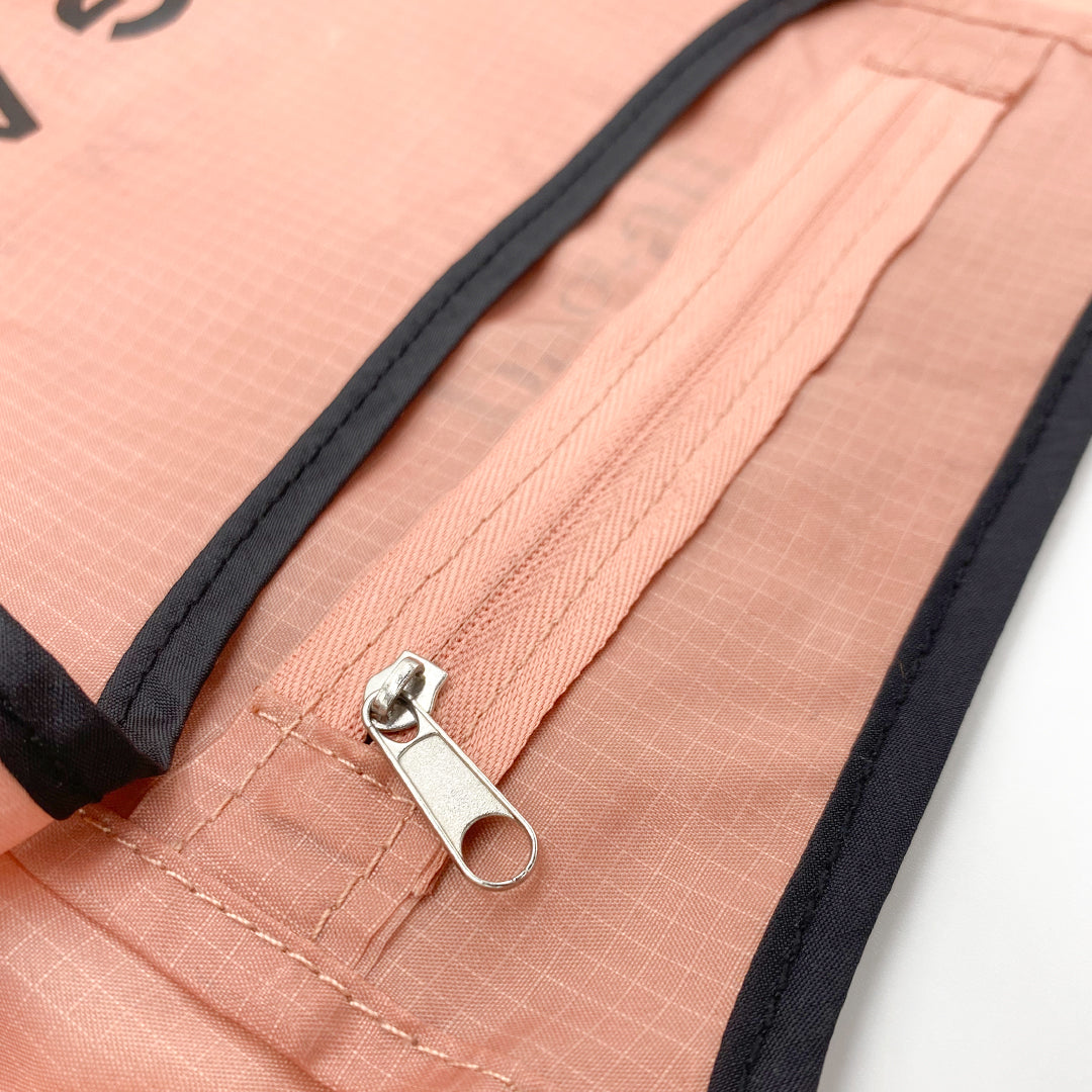 Bag-all Folding Shopping Bag with Zipper Pocket Pouch in pink and black ripstop nylon, featuring close-up detail of silver zipper pull on reinforced pocket seam with contrasting trim